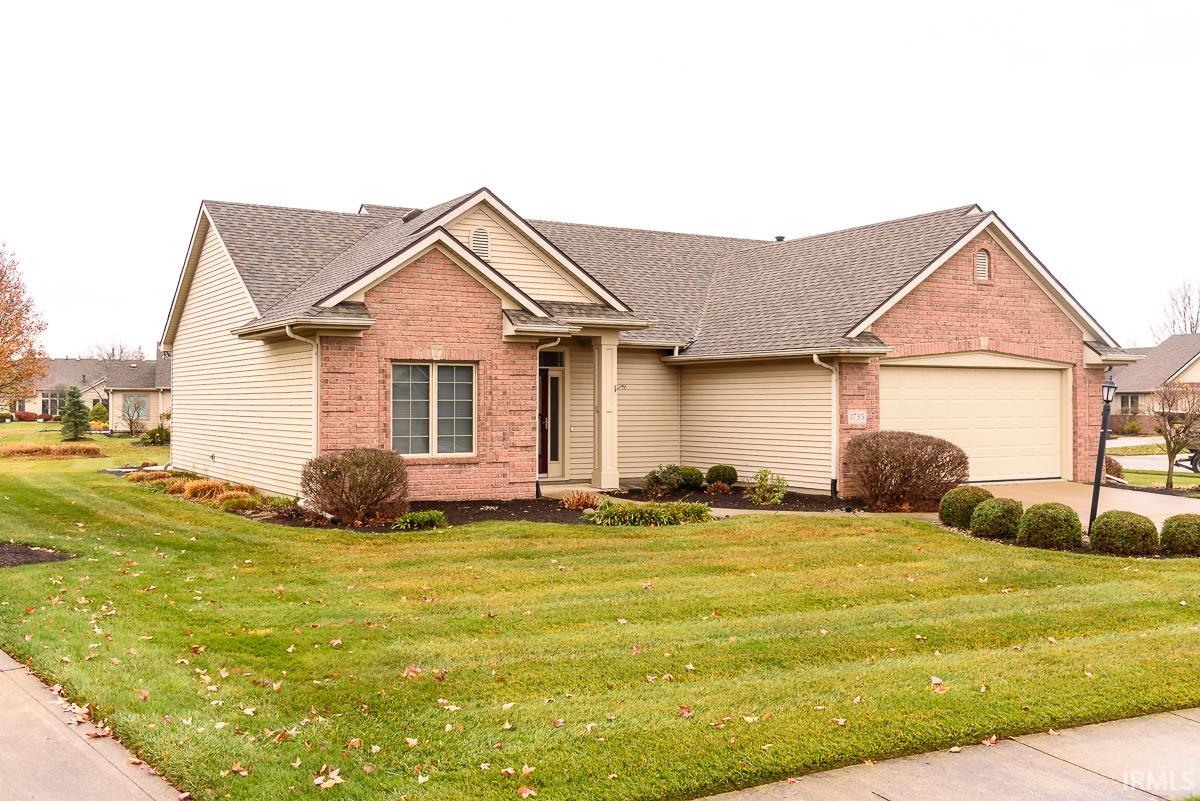 View of front of property featuring brick siding, a front yard, and roof with shingles