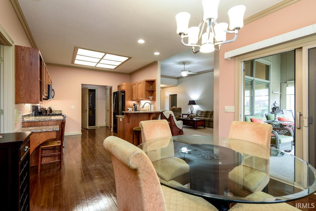 Dining room with crown molding, dark wood-style flooring, a ceiling fan, a chandelier, and recessed lighting
