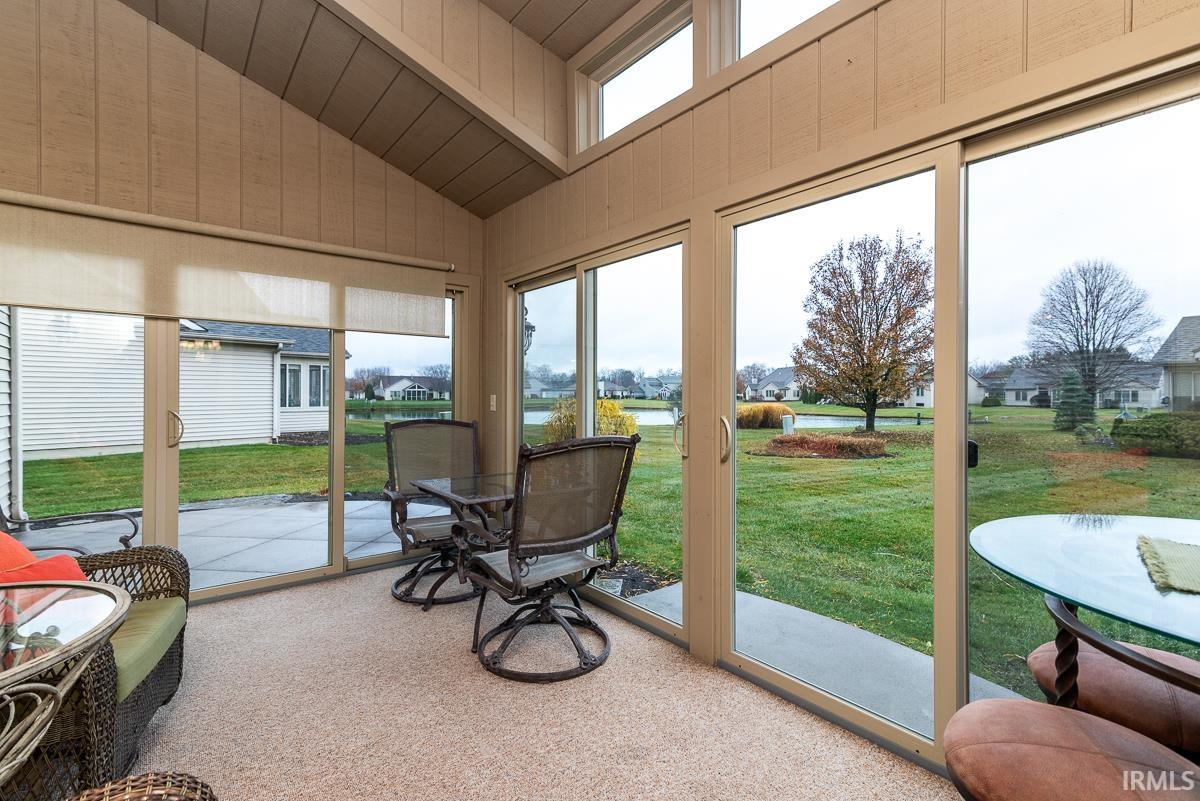 Sunroom featuring plenty of natural light, carpet flooring, high vaulted ceiling, and a water view