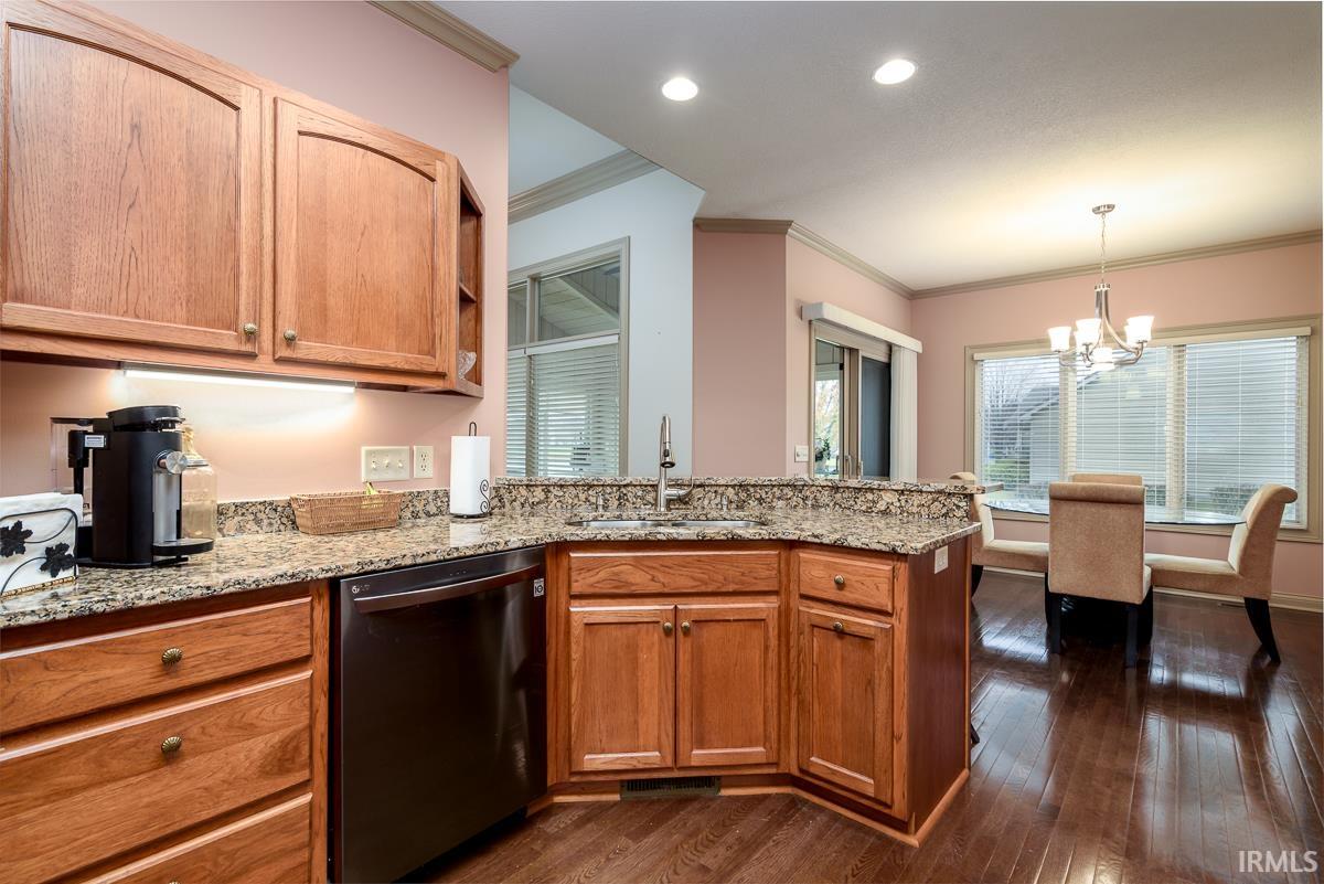 Kitchen featuring dishwasher, a chandelier, crown molding, a peninsula, and pendant lighting