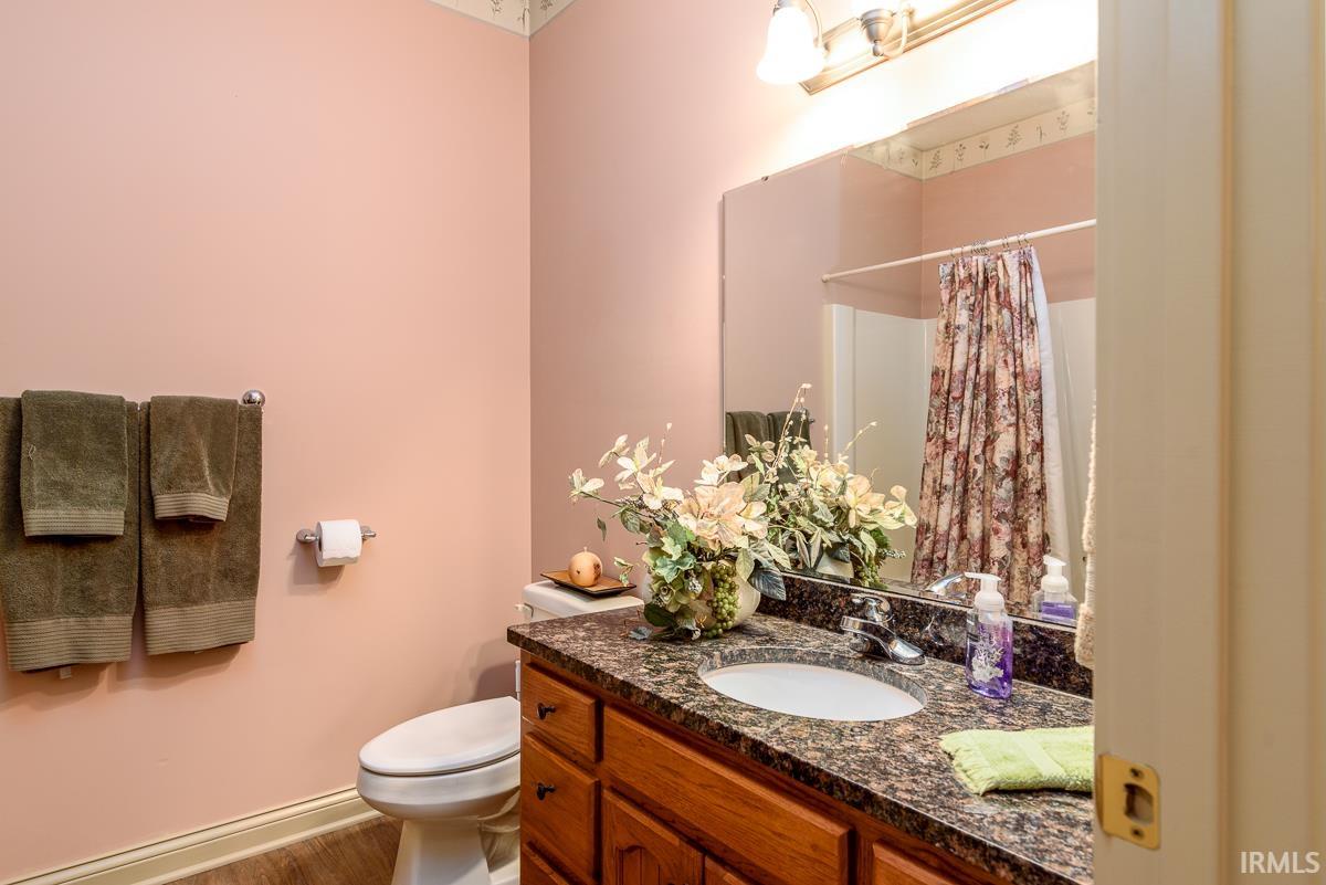 Bathroom featuring vanity, curtained shower, and wood finished floors
