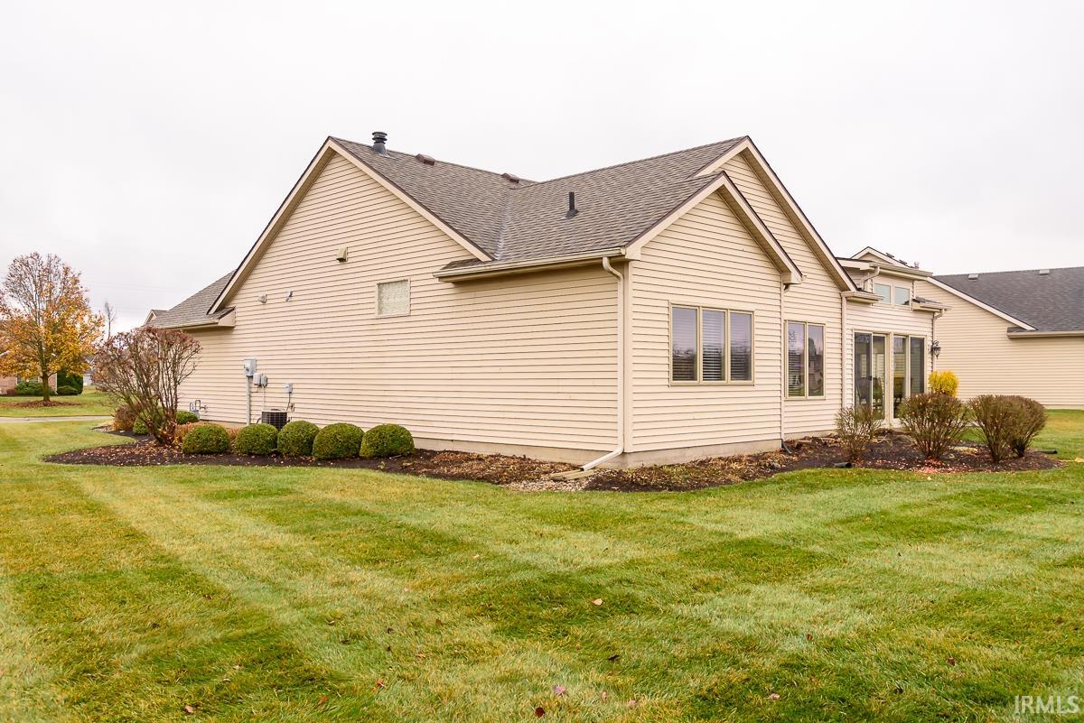 View of home's exterior with a yard and roof with shingles