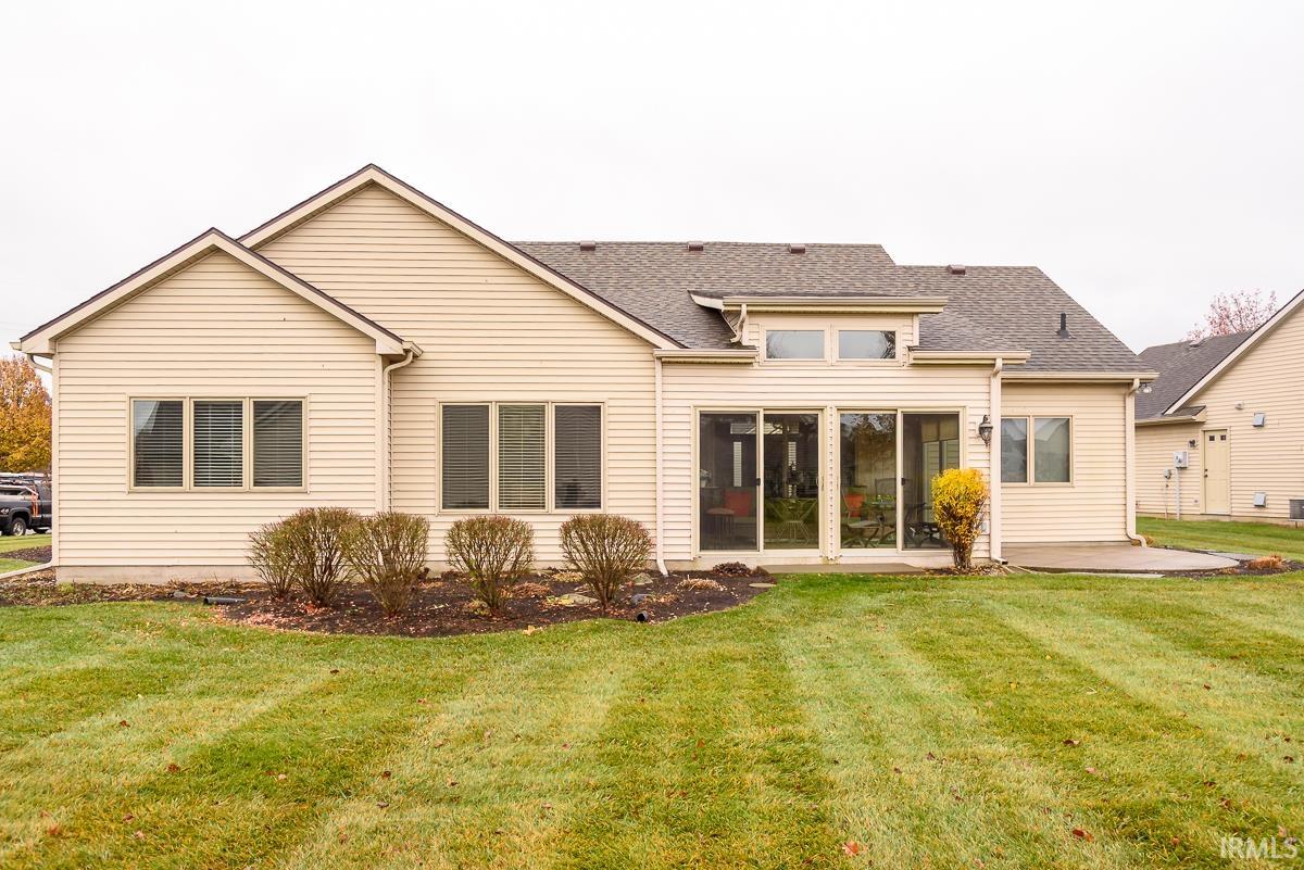 Back of property featuring a yard, roof with shingles, and a patio