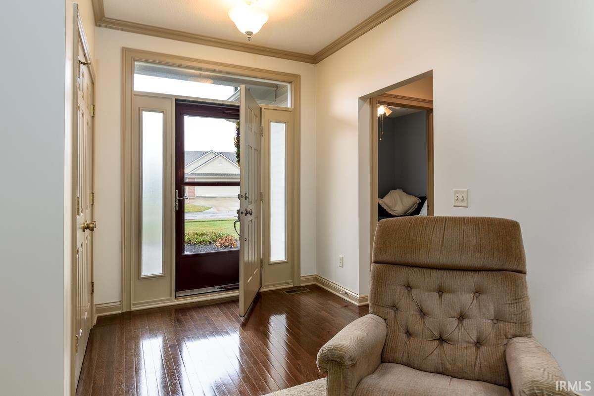 Foyer entrance with dark wood finished floors and crown molding