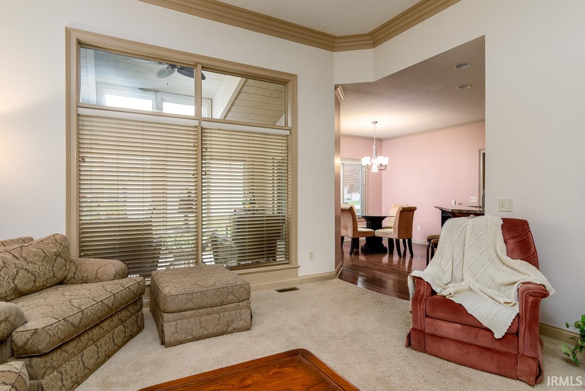 Living area with crown molding, carpet floors, and a chandelier