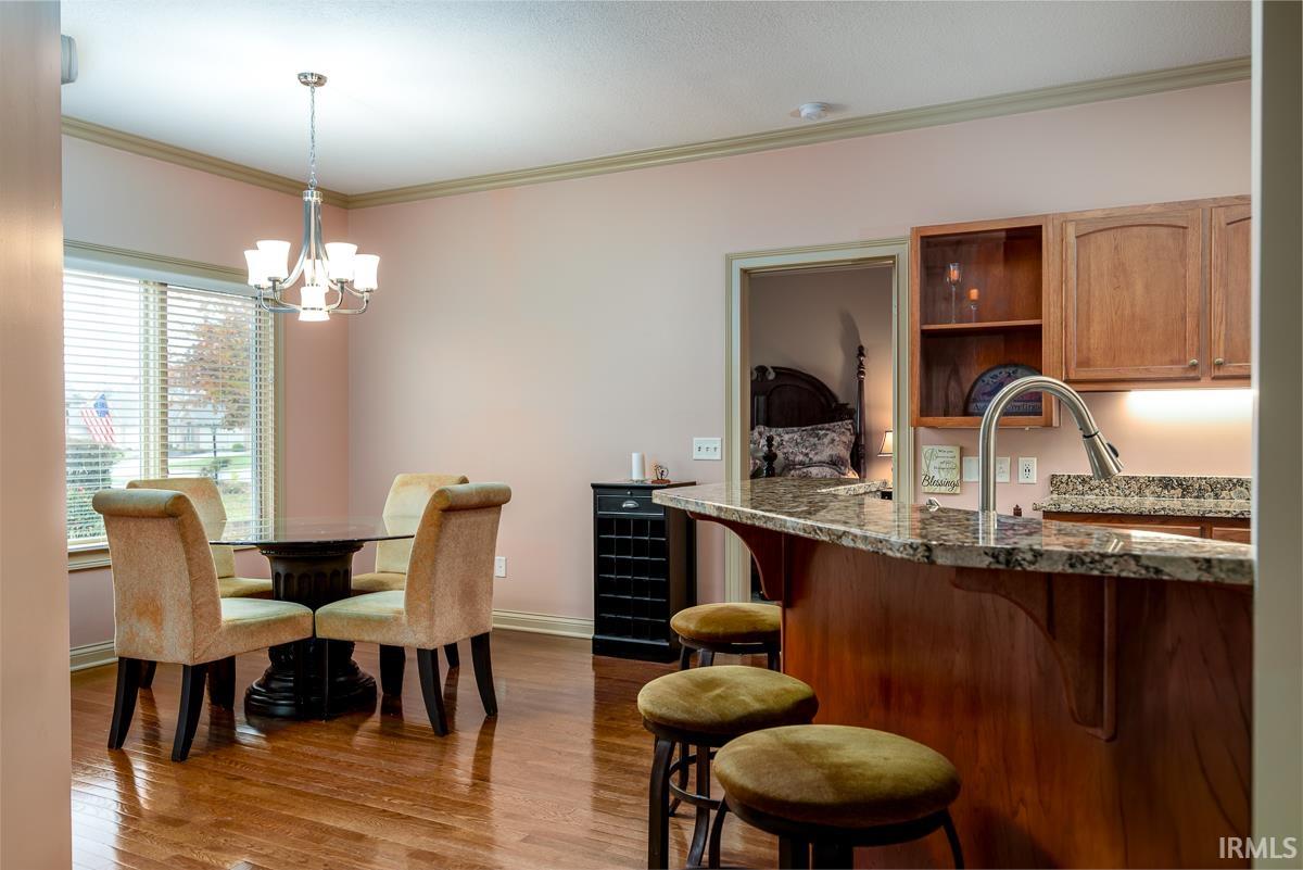 Dining room with crown molding, light wood-type flooring, and a chandelier