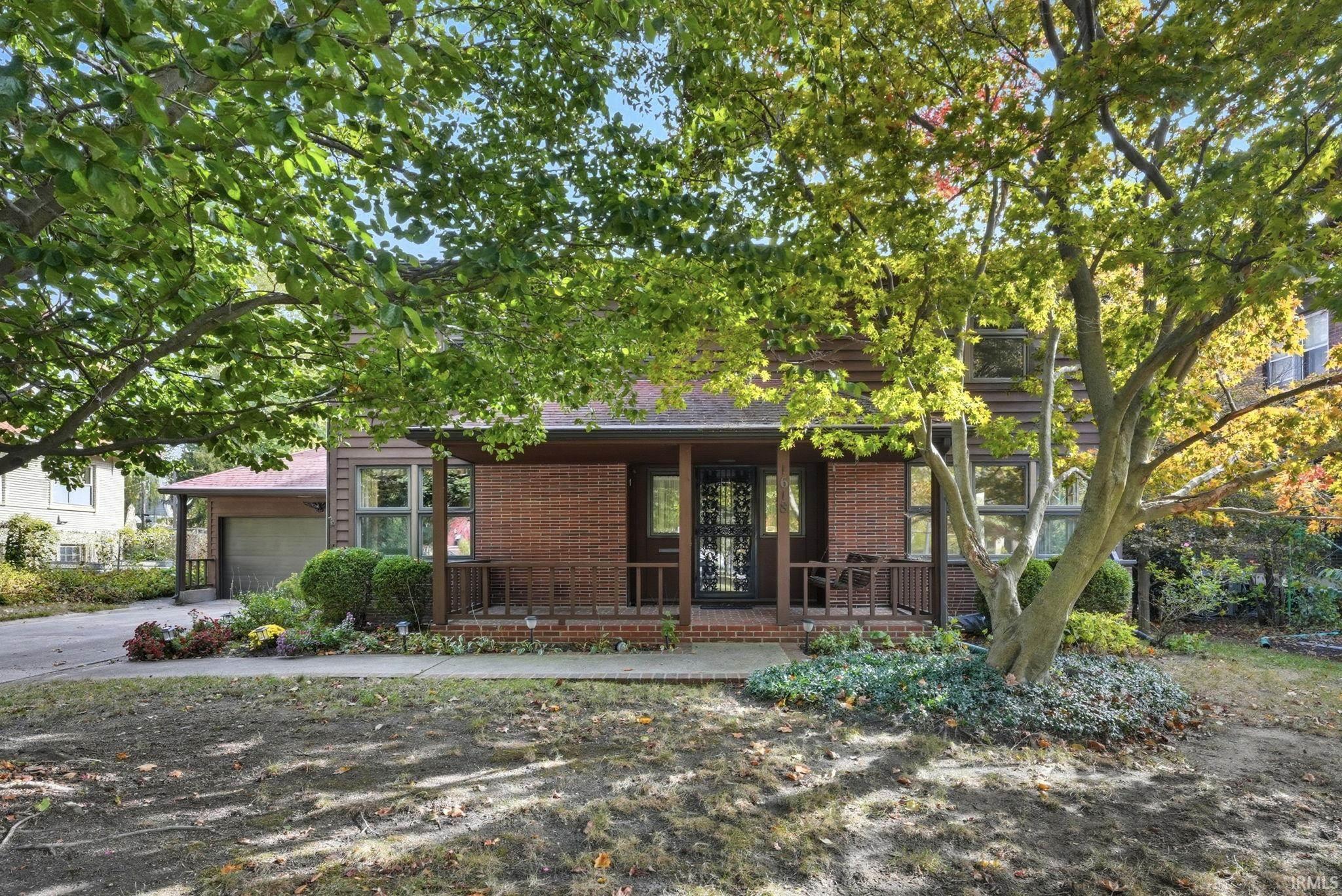View of front of property with brick siding, a porch, and driveway