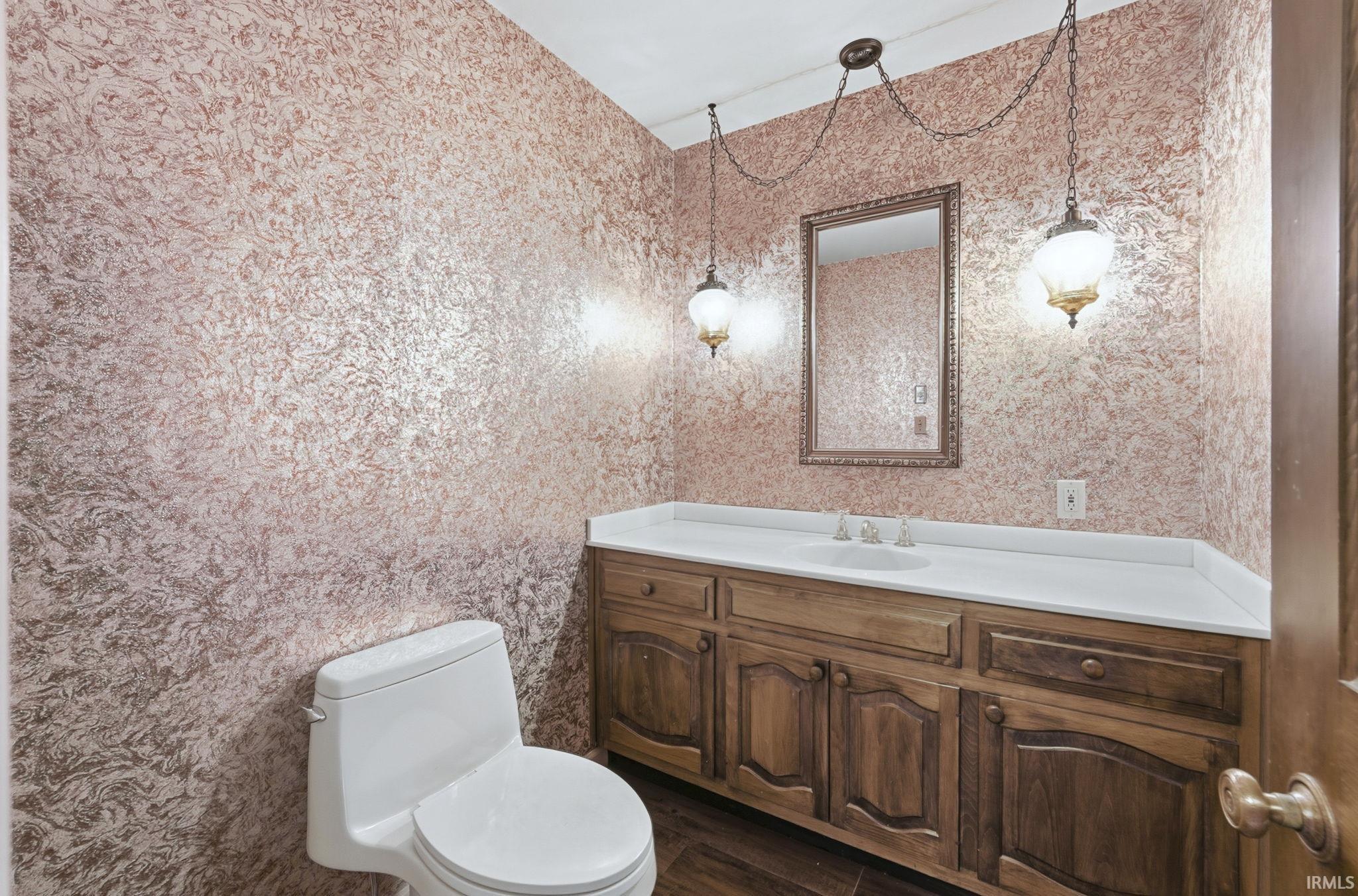 Half bath featuring vanity, dark wood-style floors, and wallpapered walls