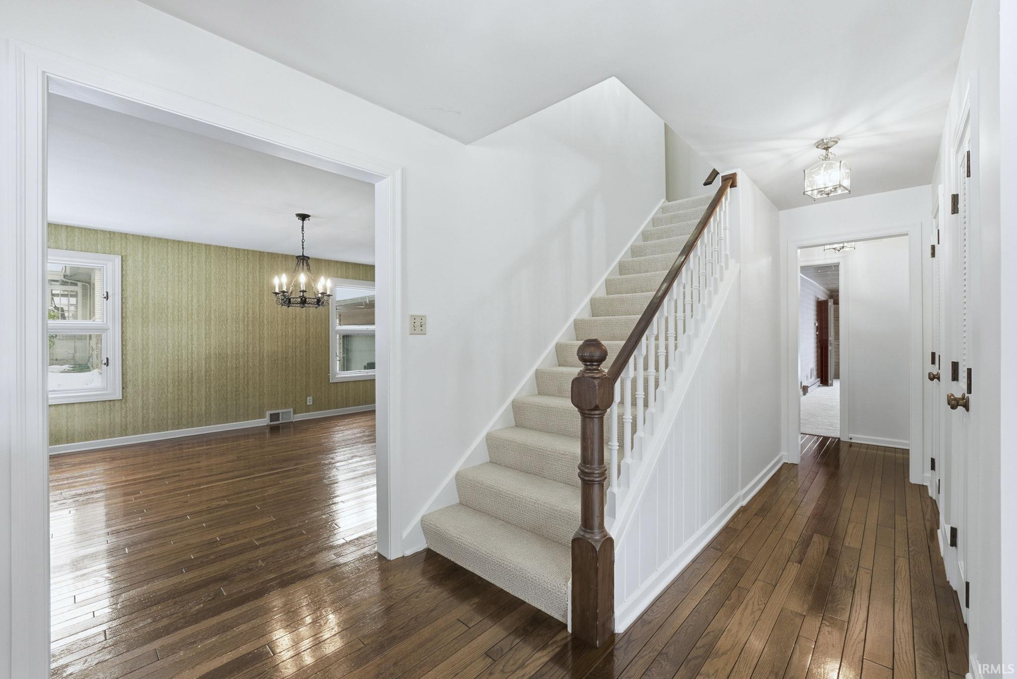 Stairs featuring a chandelier and hardwood / wood-style flooring