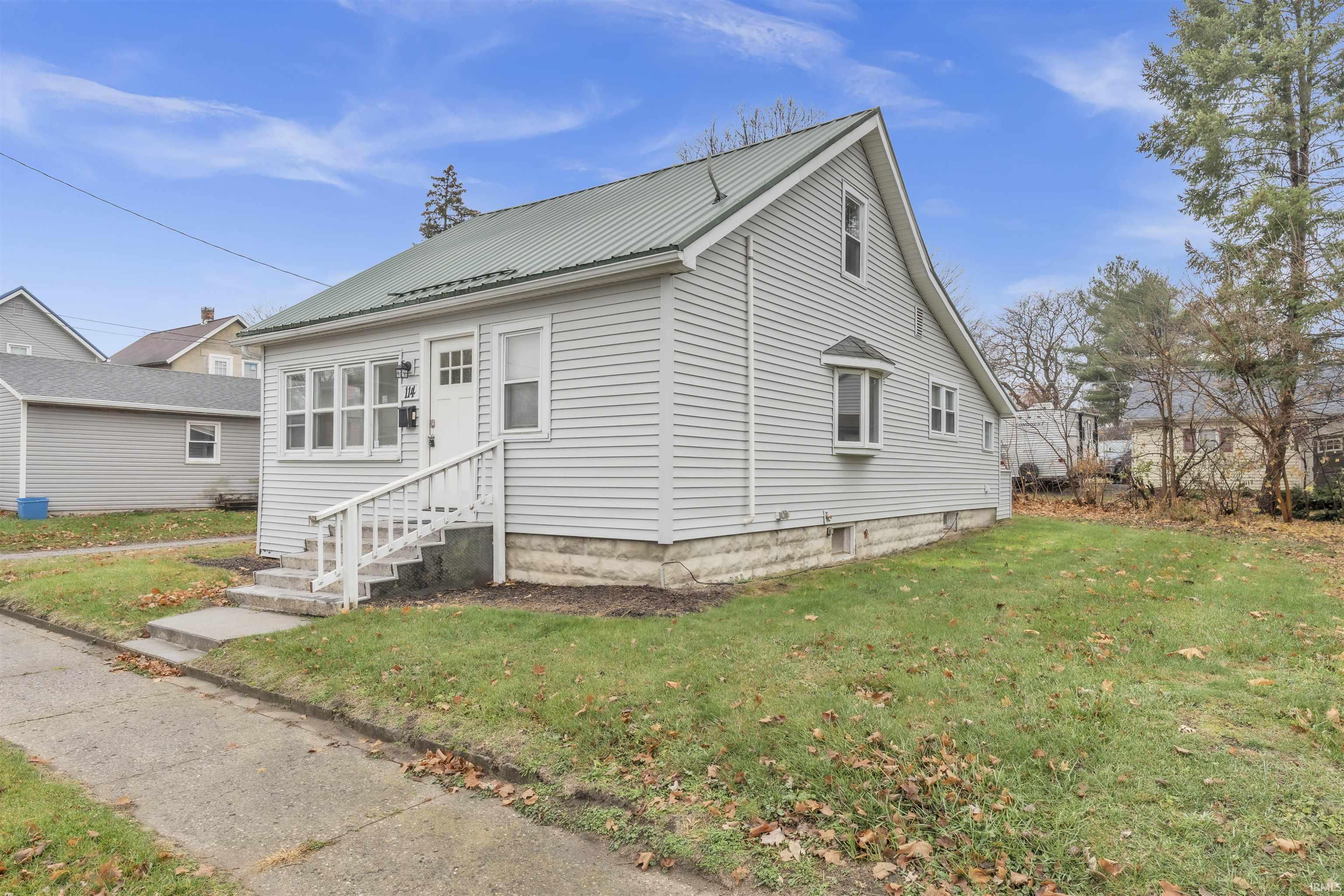 View of front of house featuring a front lawn, entry steps, and a metal roof