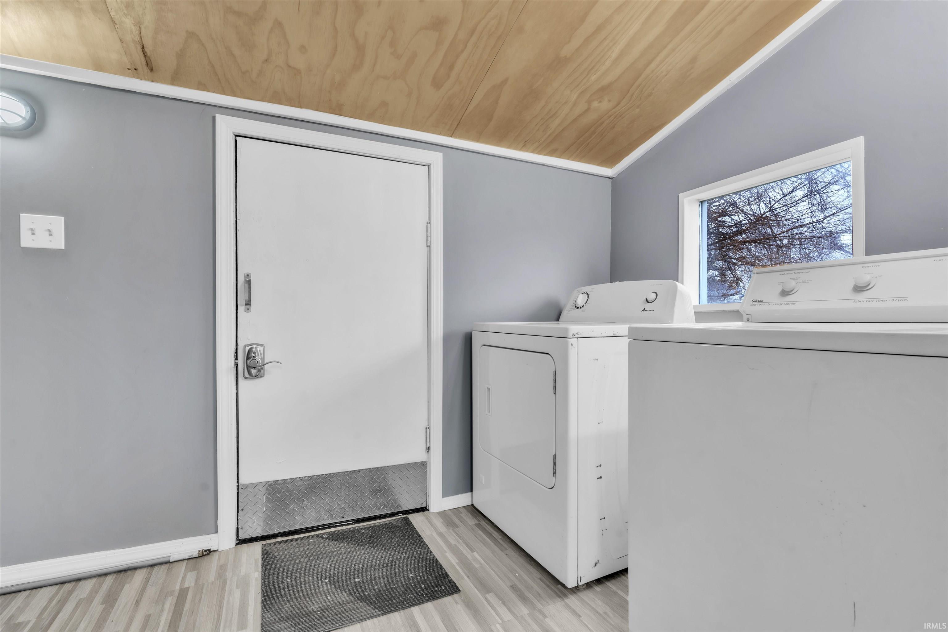Laundry room with wooden ceiling, washer and dryer, lofted ceiling, and light wood finished floors