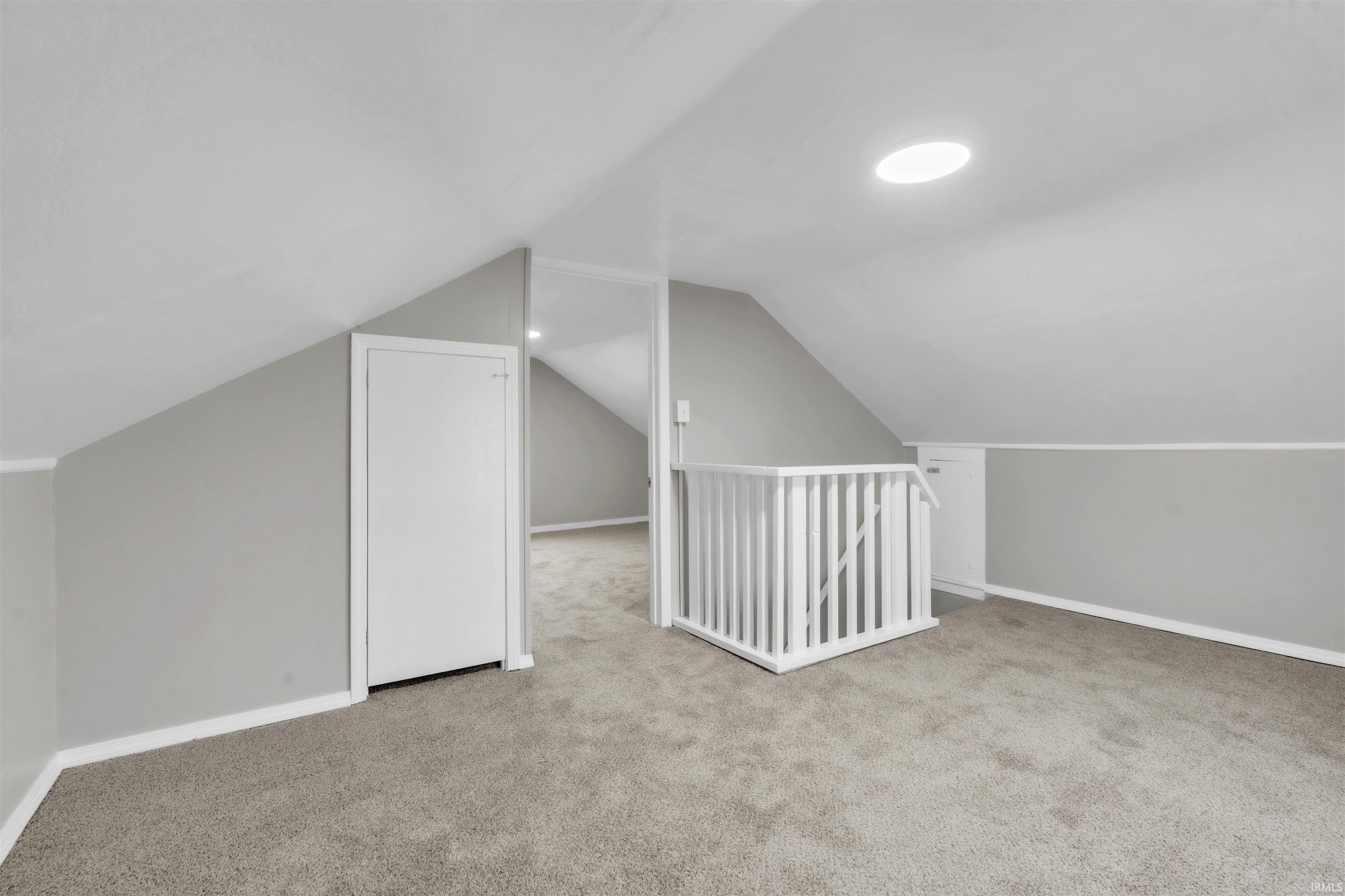 Additional living space featuring light colored carpet and vaulted ceiling
