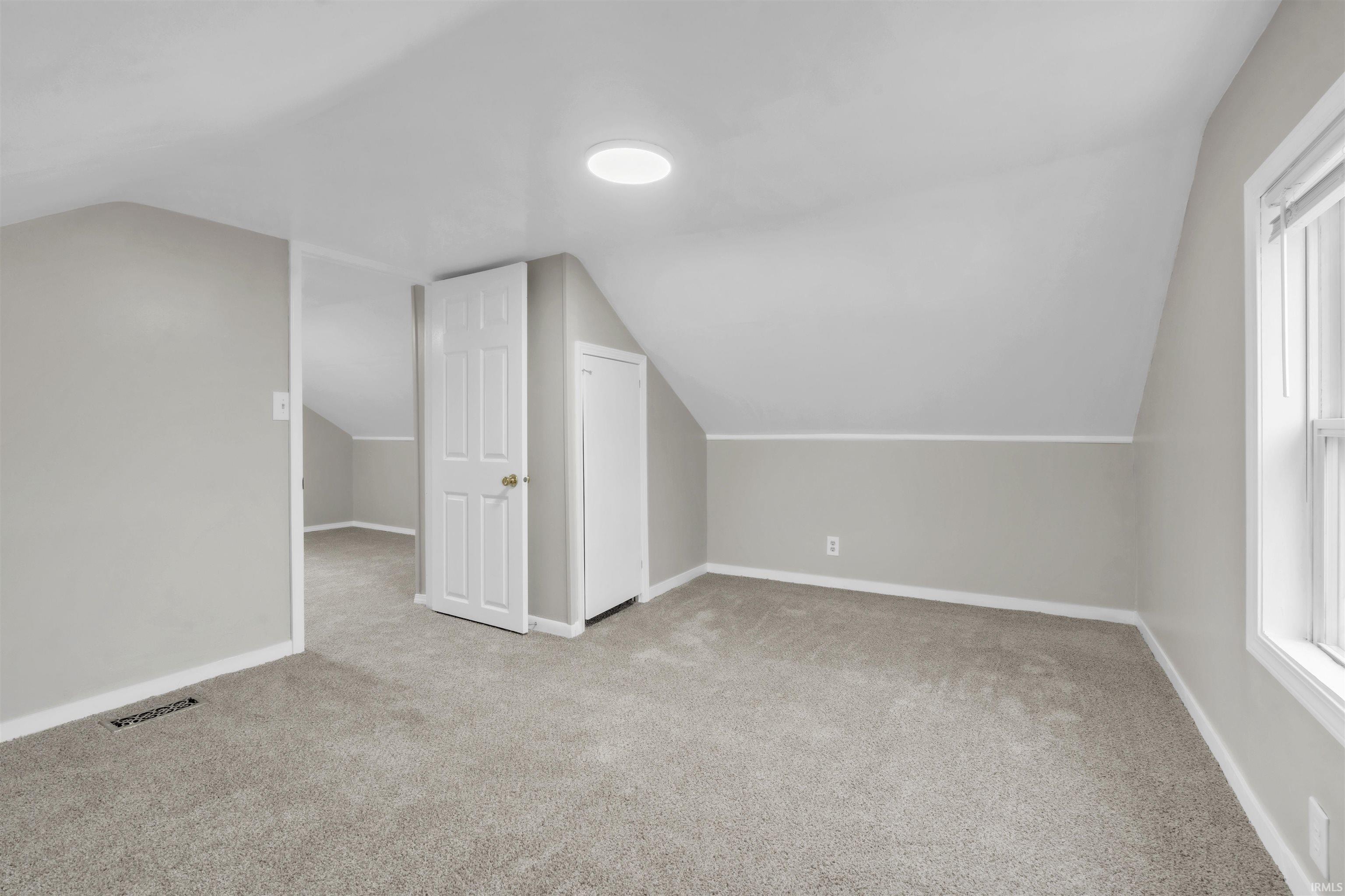 Bonus room with light carpet and lofted ceiling