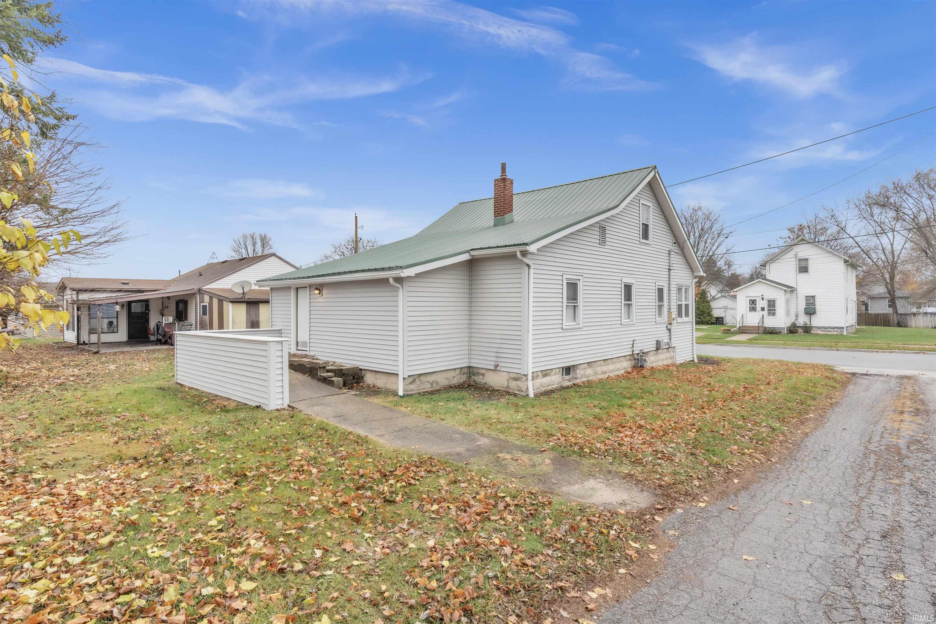 View of property exterior with a metal roof, a chimney, and a yard