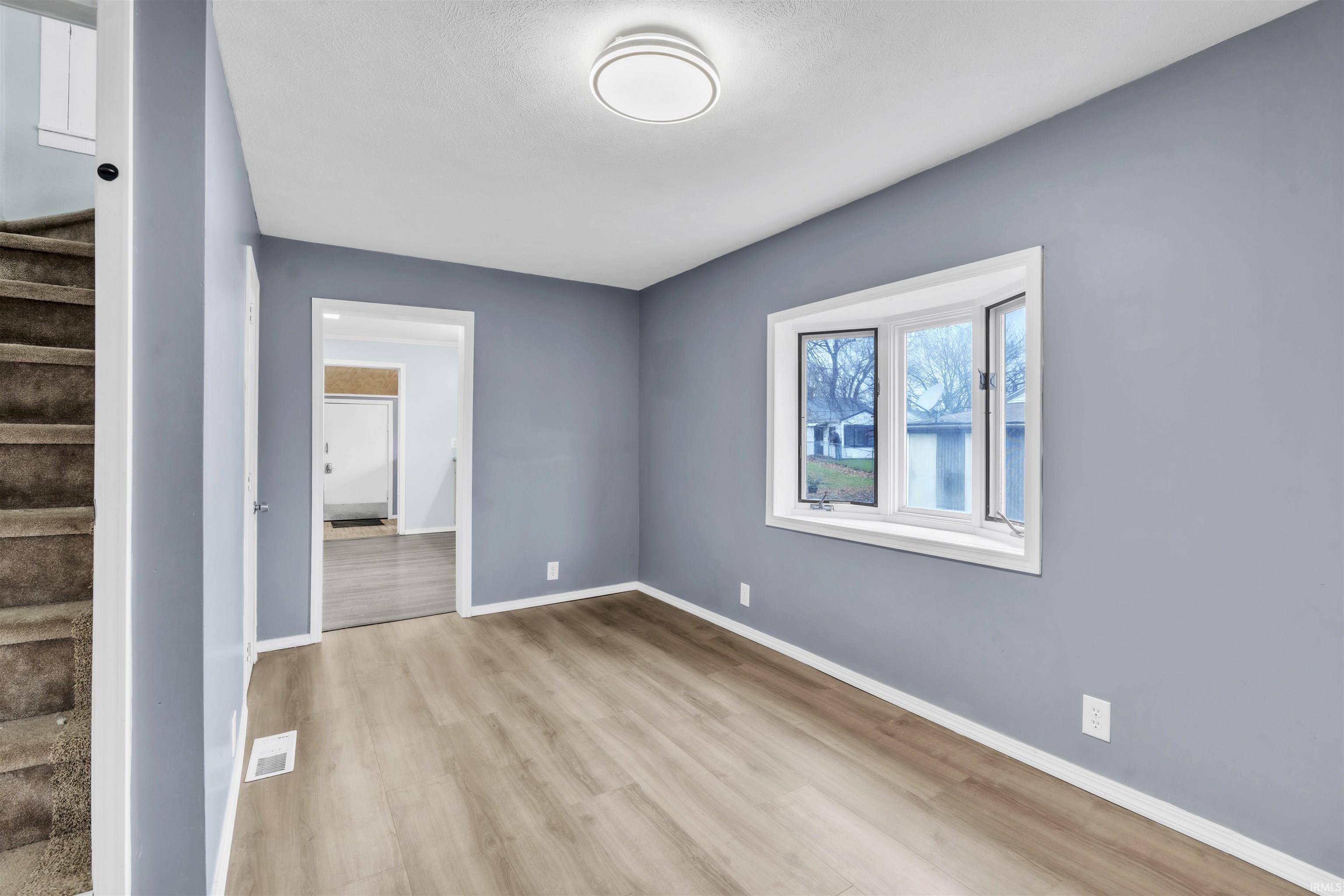 Empty room with light wood-type flooring and stairs