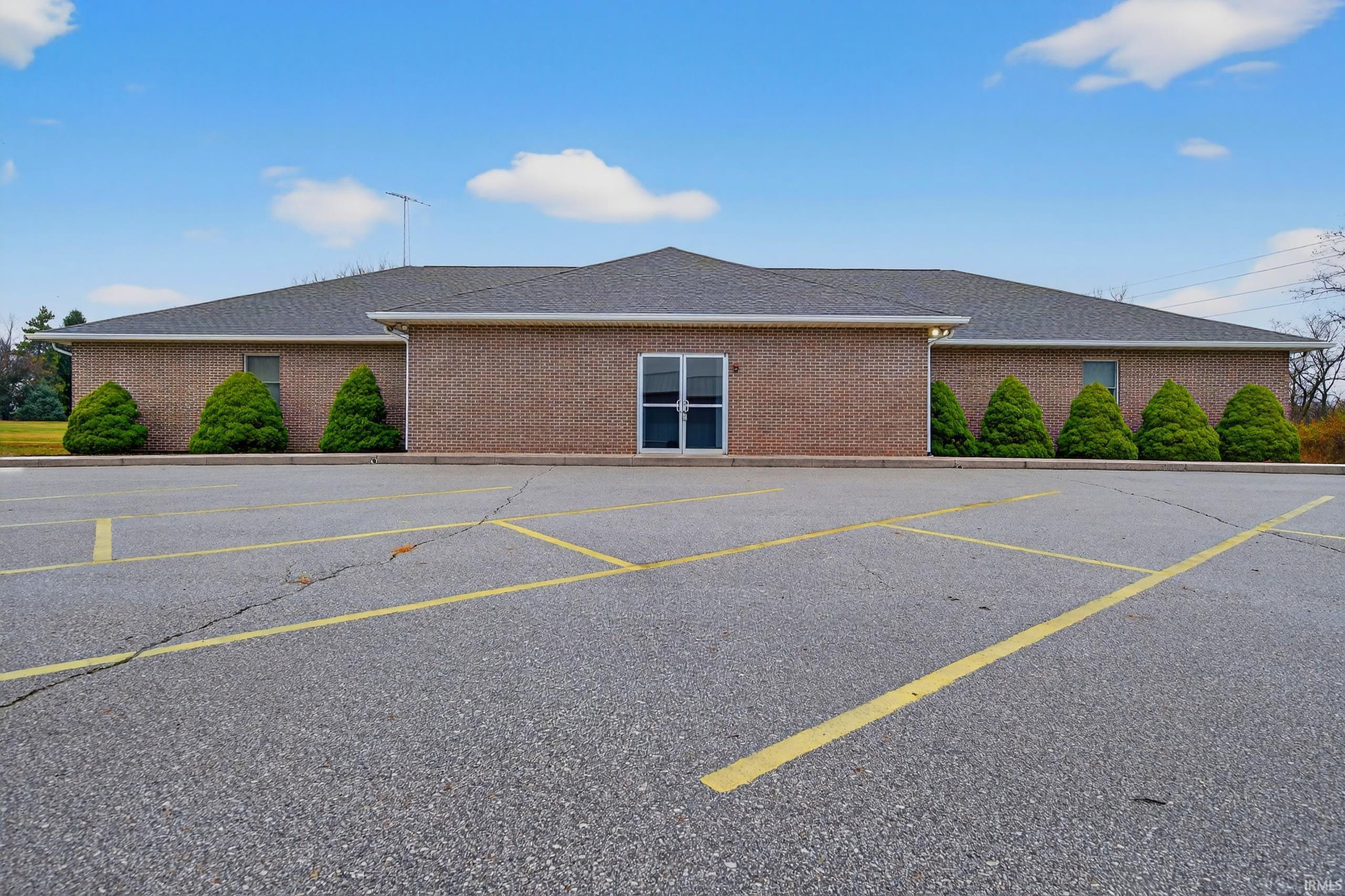 View of front of house featuring roof with shingles, uncovered parking, and brick siding