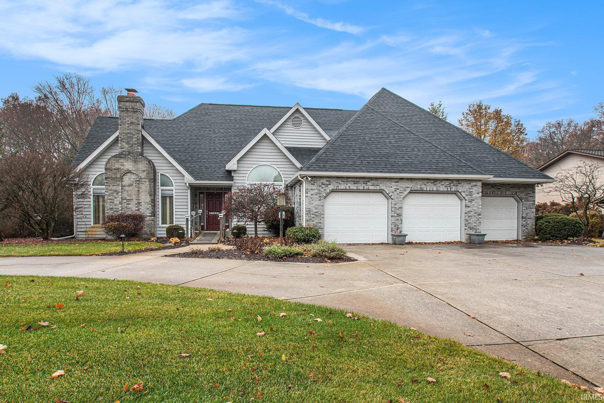 Traditional-style home featuring  U U-shaped driveway, a front lawn, a shingled roof, and an attached garage.