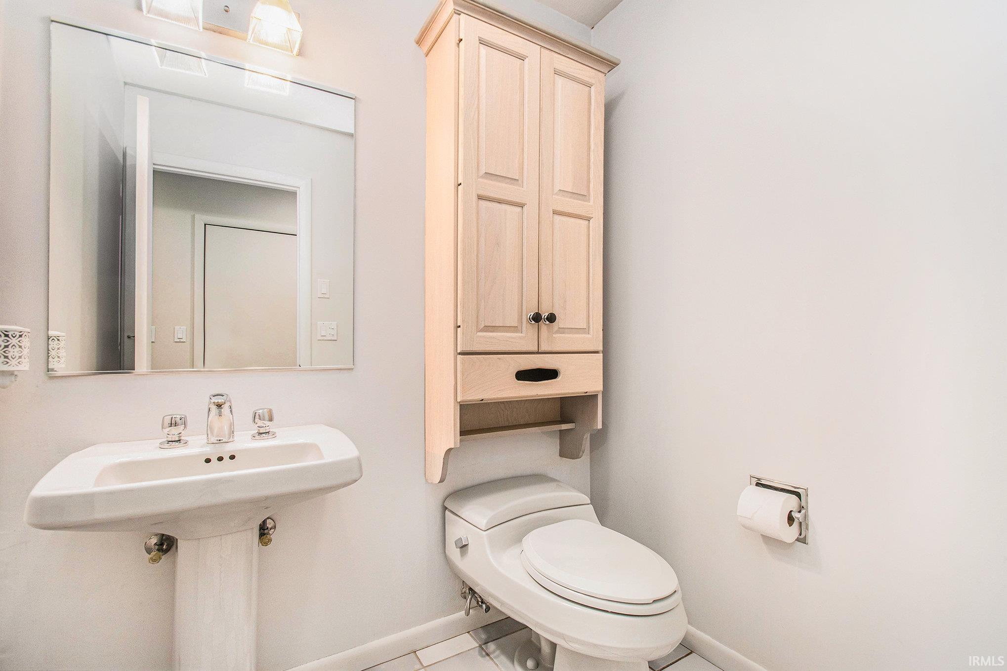 Half bathroom with toilet and tile patterned flooring. Main floor.