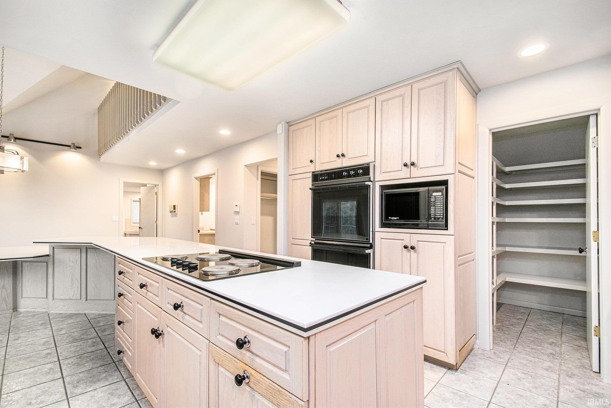 Kitchen with a kitchen island, black appliances, recessed lighting, light tile patterned floors, and light countertops