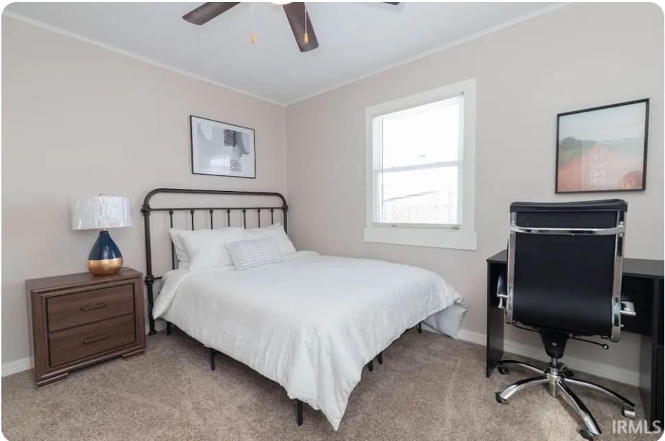 Bedroom with ornamental molding, carpet flooring, ceiling fan, and a desk