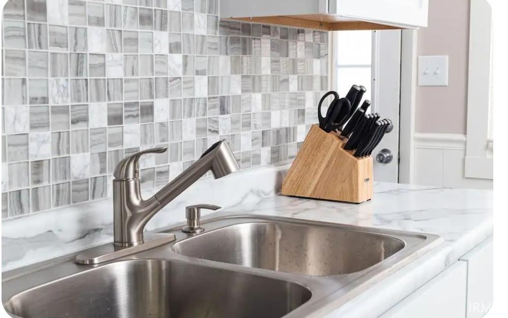 Kitchen view of white cabinets, light stone countertops, and decorative backsplash