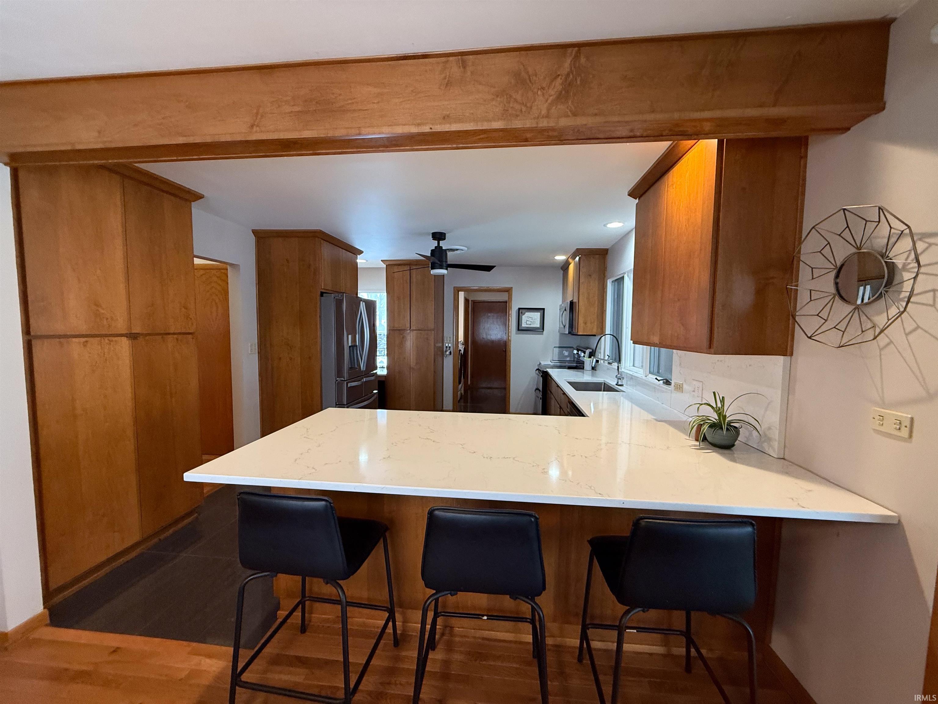 Kitchen with brown cabinets, a peninsula, a kitchen breakfast bar, and recessed lighting