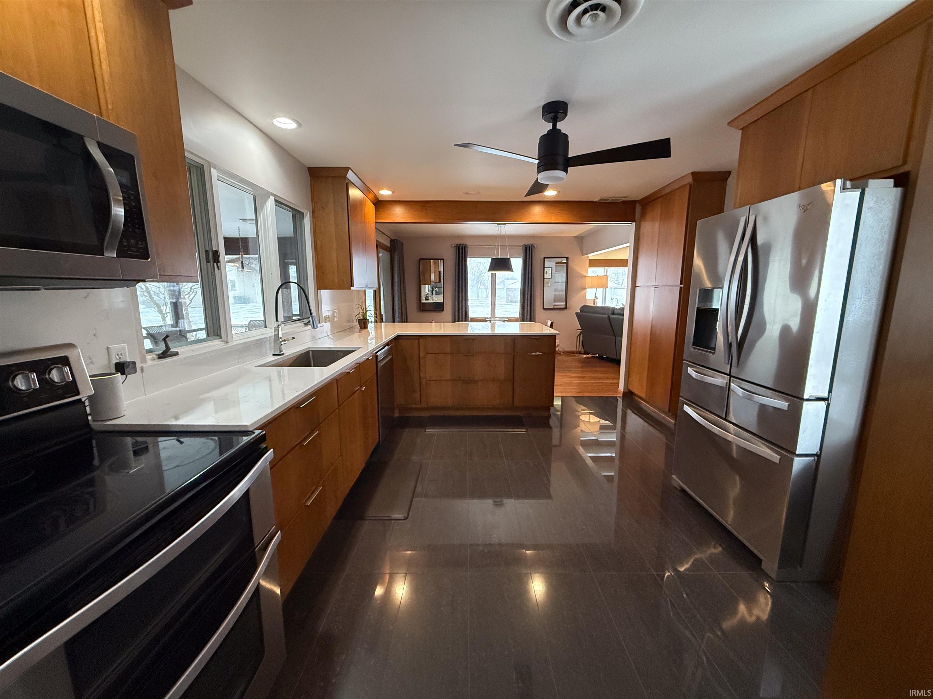 Kitchen featuring stainless steel appliances, a peninsula, brown cabinets, and recessed lighting