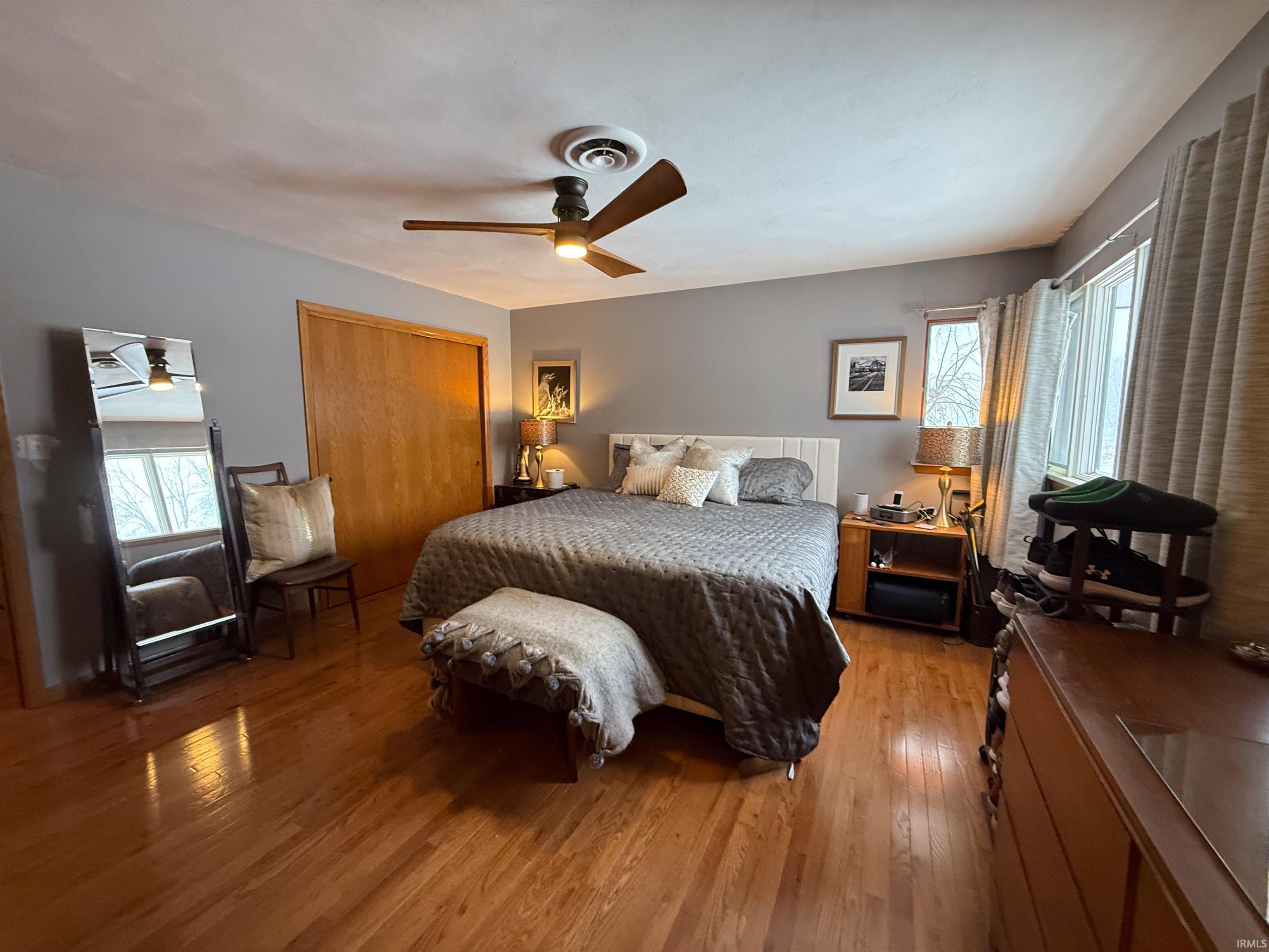 Bedroom featuring multiple windows, a closet, light wood-style floors, and a ceiling fan