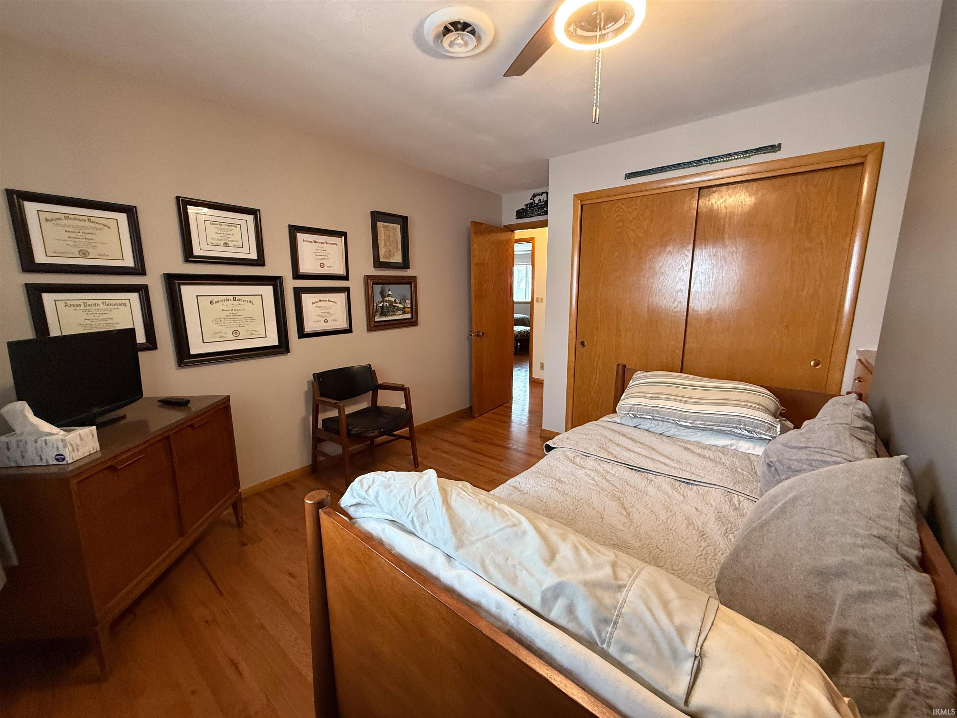 Bedroom with light wood-style flooring, a closet, and ceiling fan