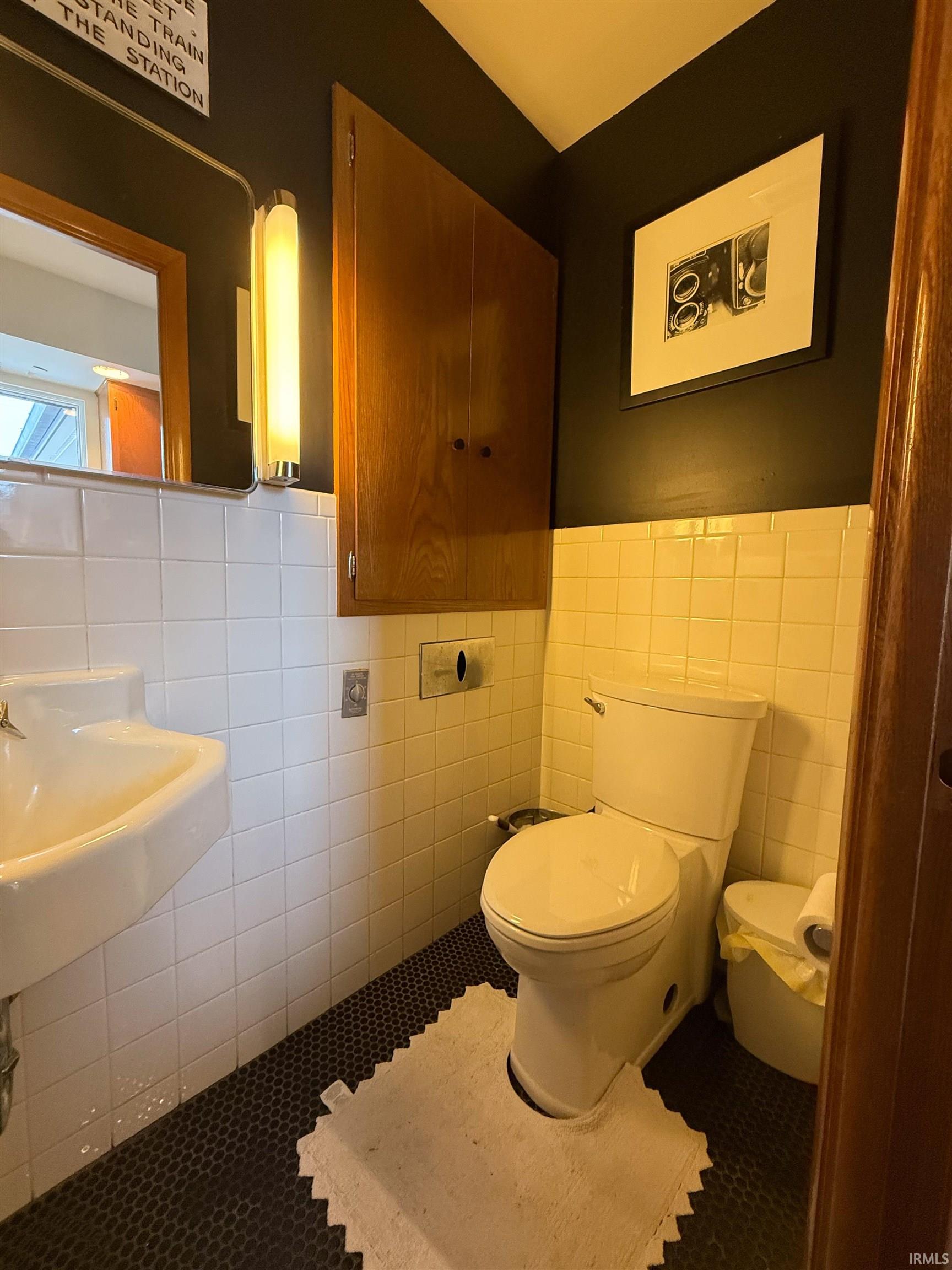 Bathroom featuring tile walls, tile patterned flooring, and wainscoting
