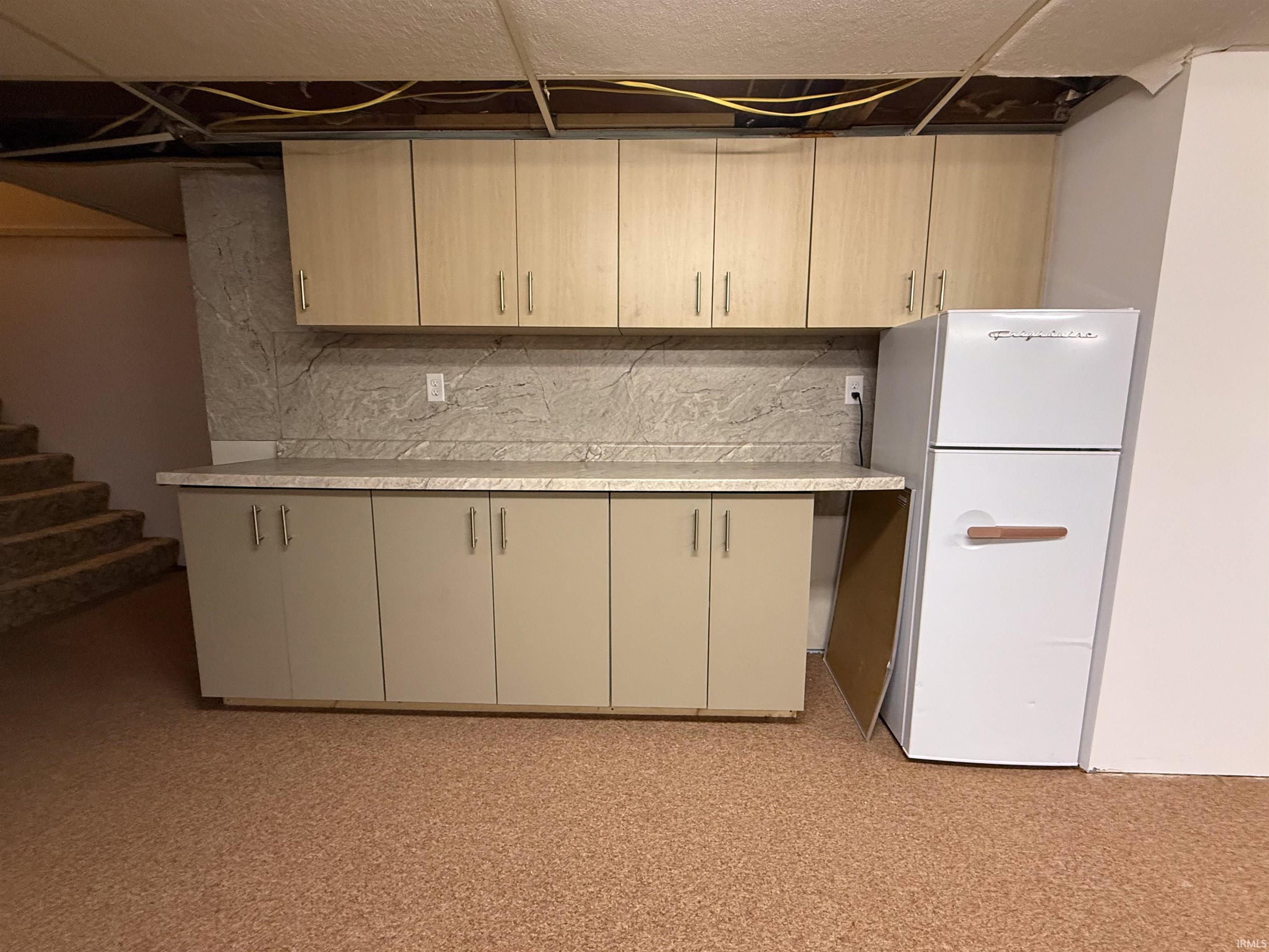 Kitchen with light countertops, freestanding refrigerator, and tasteful backsplash