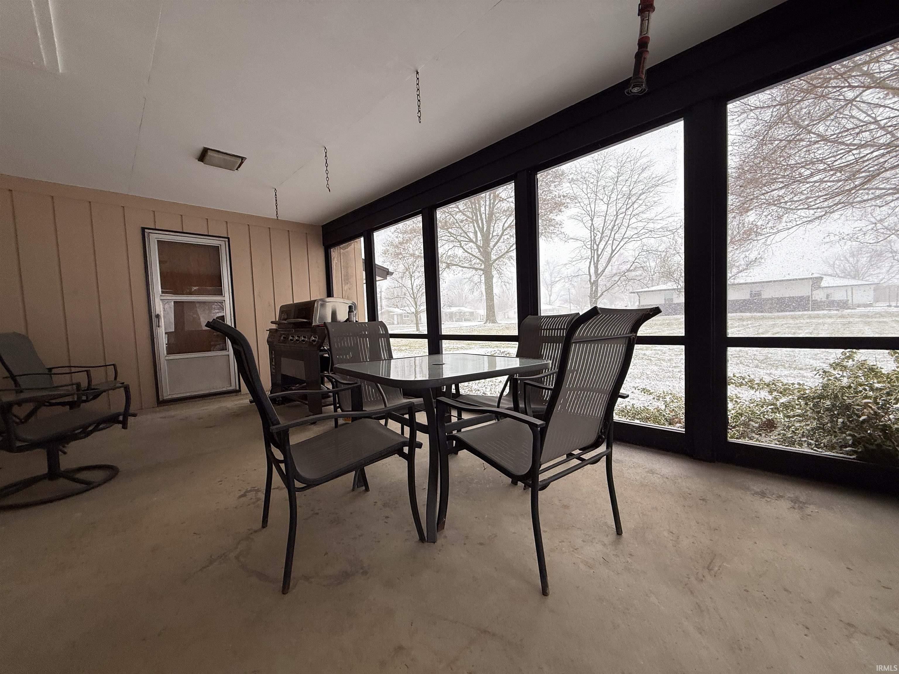Sunroom / solarium with unfinished concrete flooring and wood walls