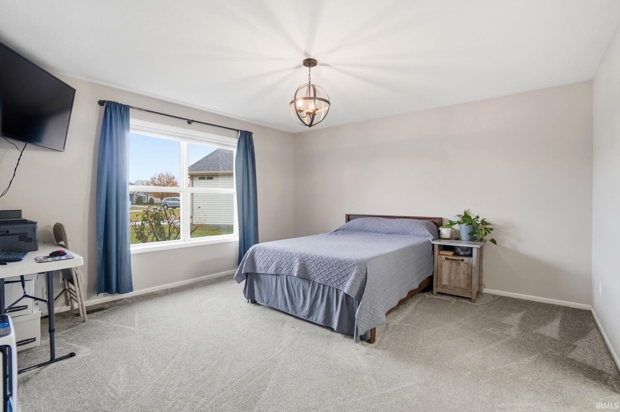 Carpeted bedroom with baseboards and a chandelier