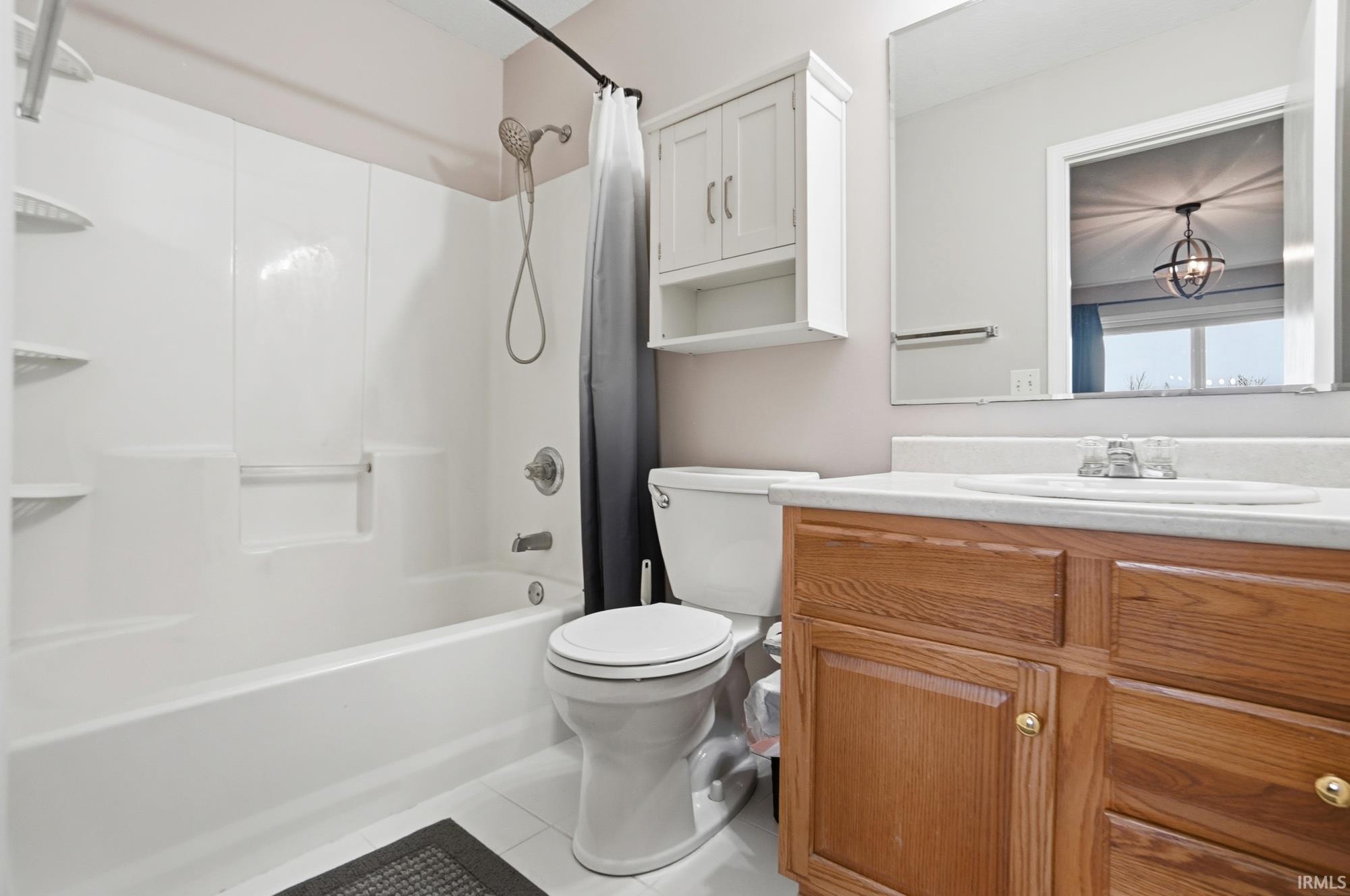 Bathroom with shower / bath combo with shower curtain, vanity, and light tile patterned flooring