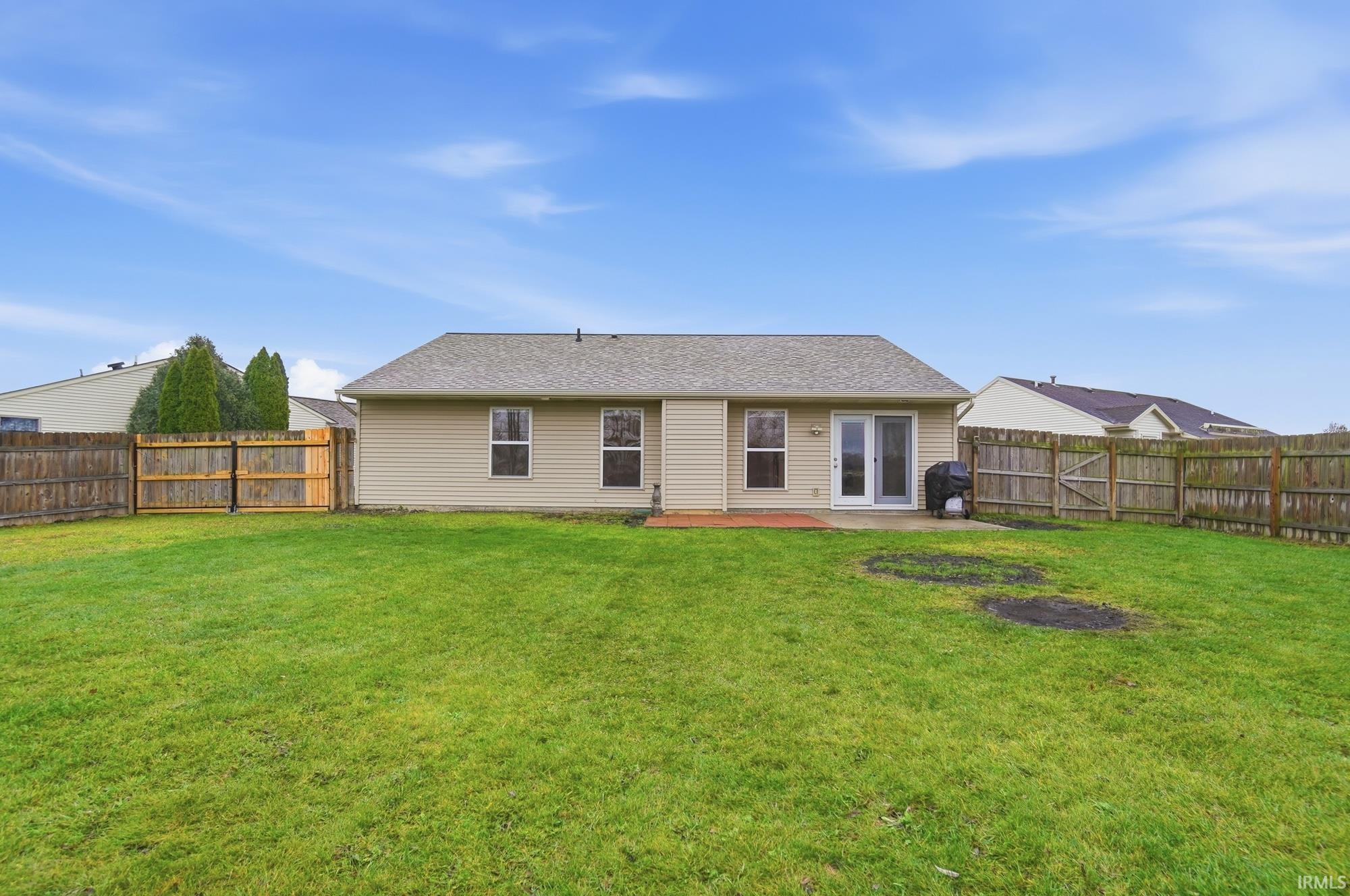 Rear view of house with a patio area, a fenced backyard, and roof with shingles