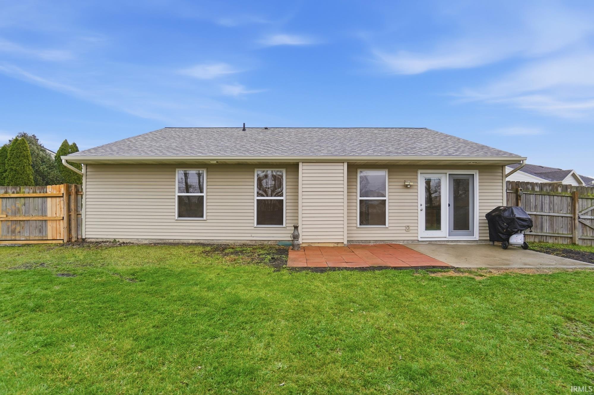 Rear view of house with a shingled roof, a fenced backyard, and a patio area