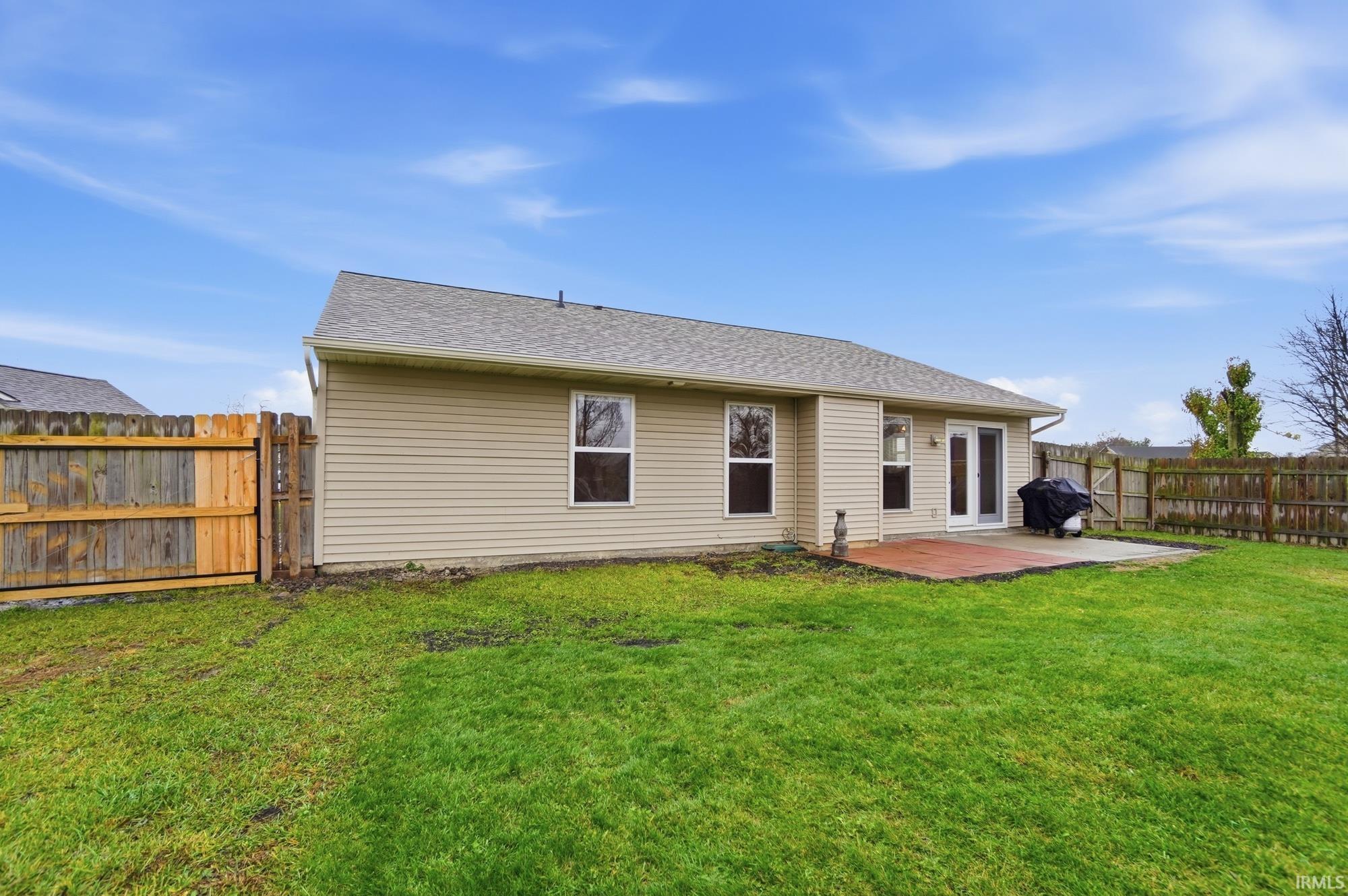 Back of property with a fenced backyard, roof with shingles, and a wooden deck