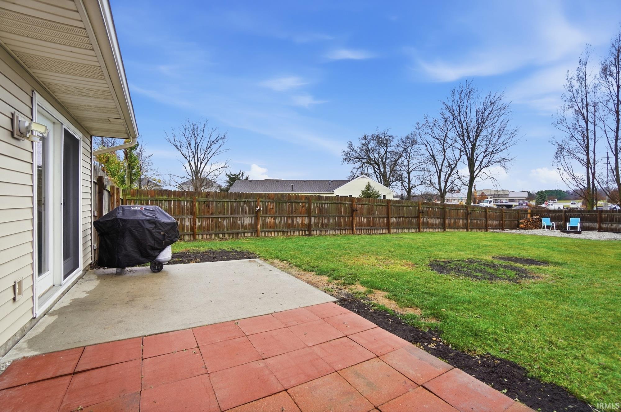 Fenced backyard with a patio and area for grilling