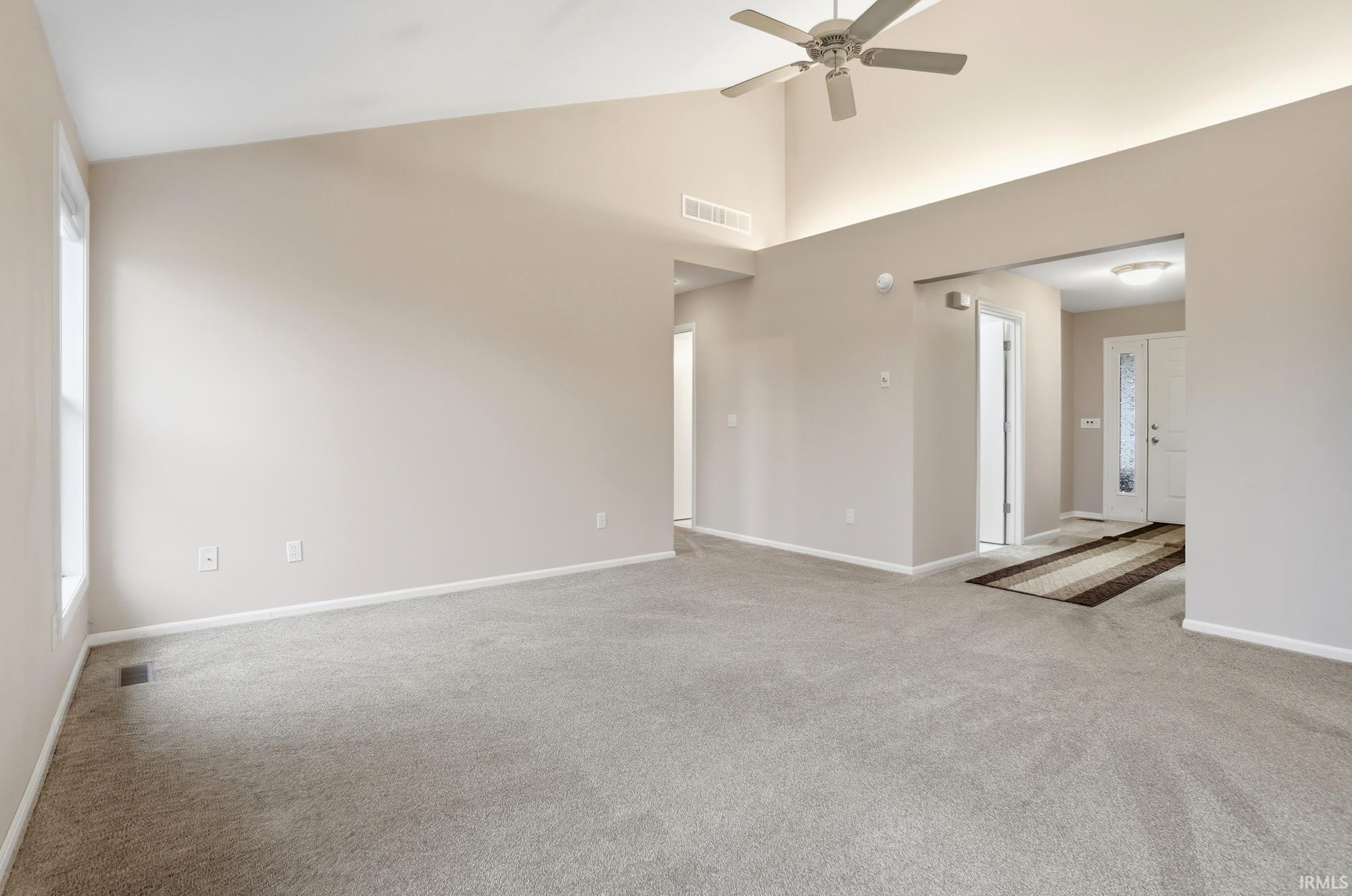 Unfurnished living room featuring high vaulted ceiling, light colored carpet, and a ceiling fan