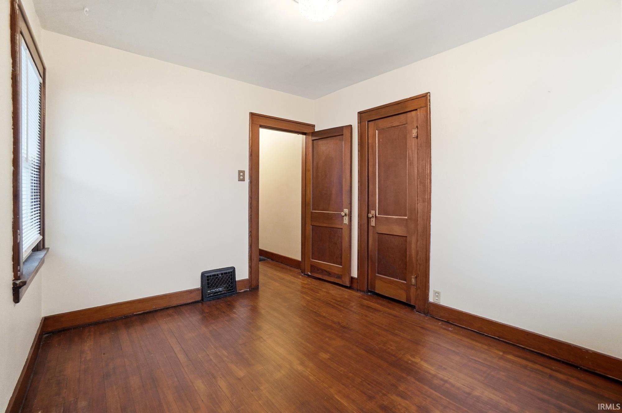 Unfurnished bedroom with dark wood-style flooring and a closet