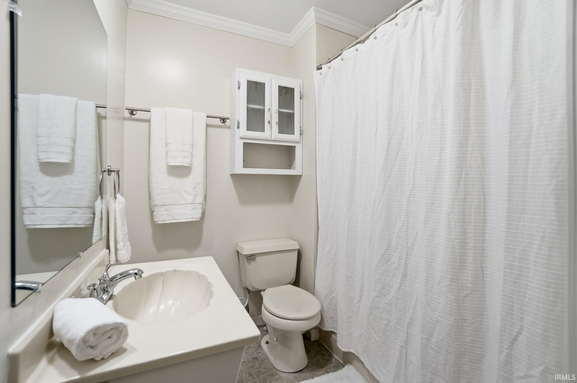 Bathroom featuring a shower with shower curtain, ornamental molding, and vanity