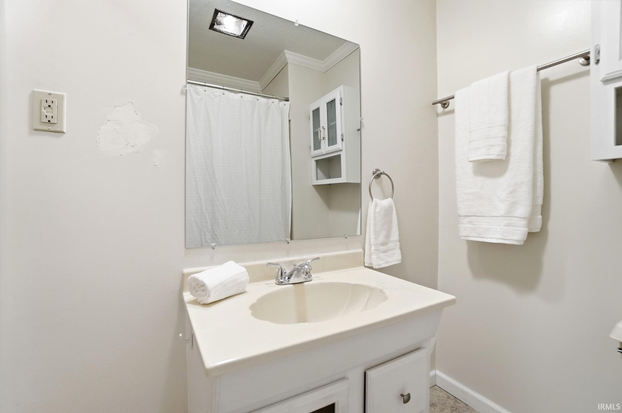 Bathroom with vanity, crown molding, and curtained shower