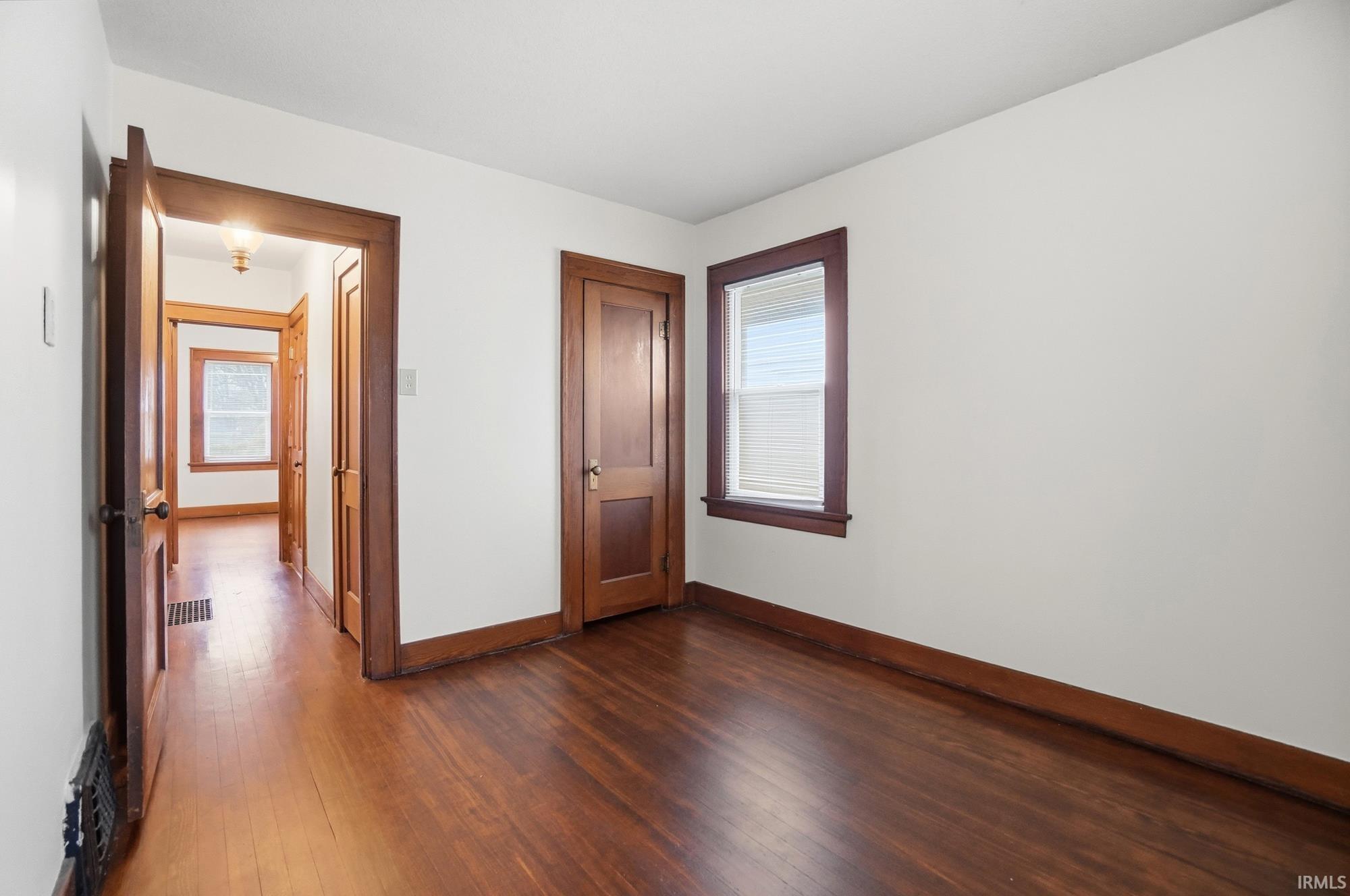 Unfurnished bedroom featuring baseboards and dark wood-style floors