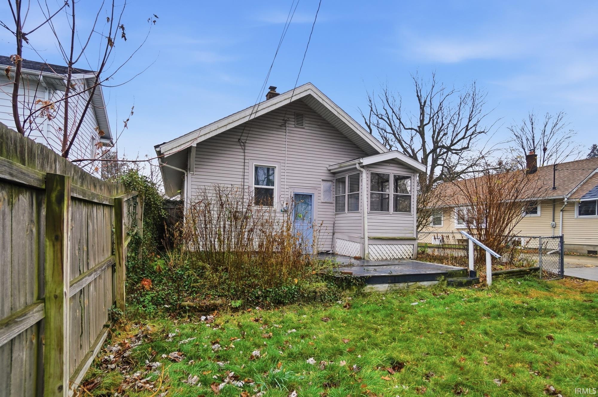 Rear view of house with a sunroom, a wooden deck, and a gate
