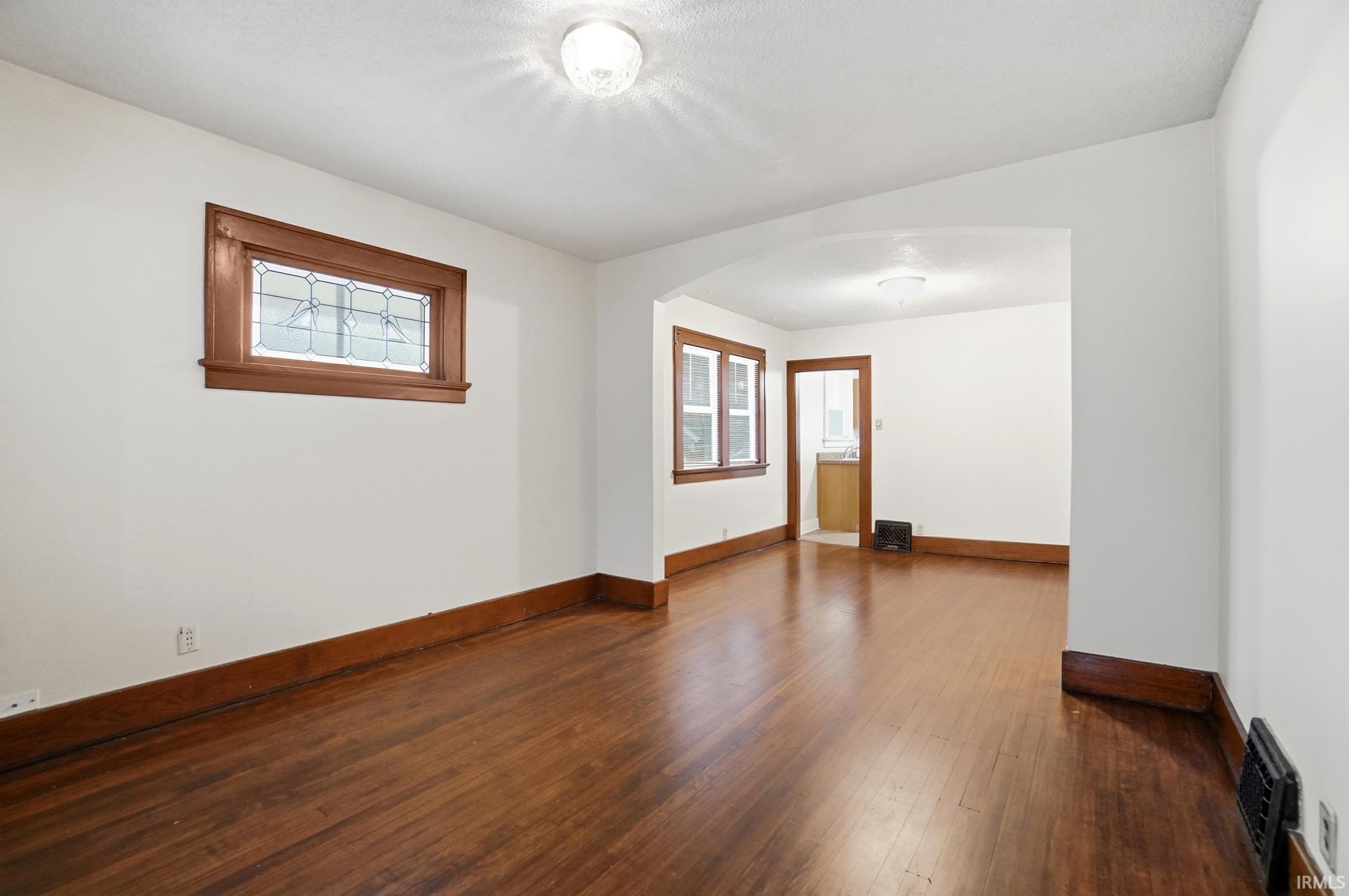 Spare room featuring arched walkways and dark wood-style floors