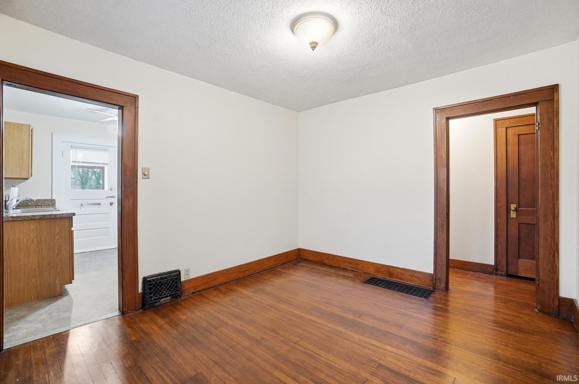 Unfurnished room with dark wood finished floors and a textured ceiling
