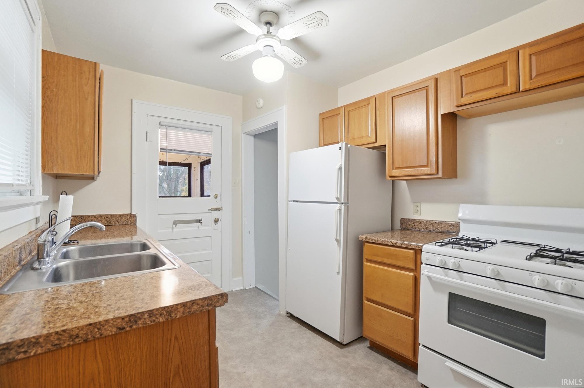 Kitchen with white appliances and a ceiling fan