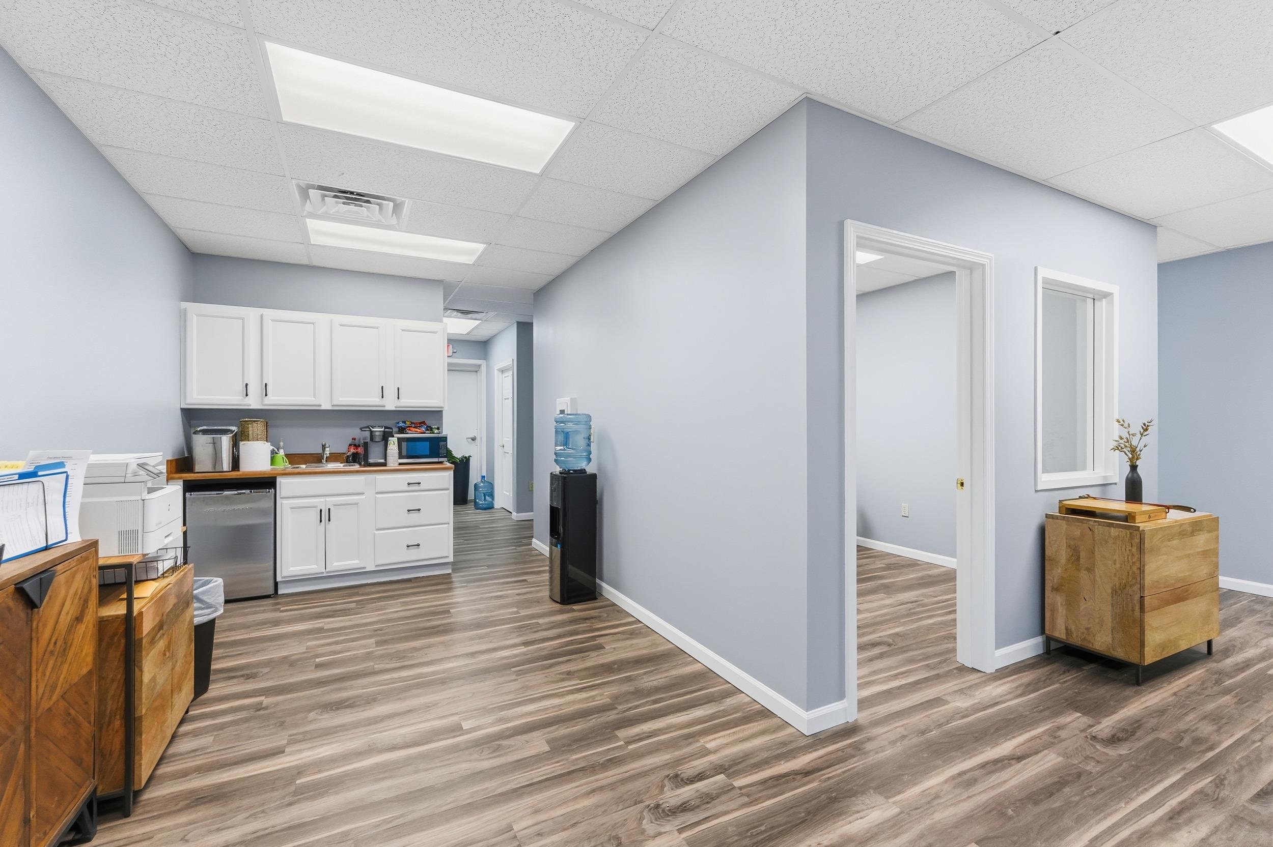 Kitchen with white cabinetry, light wood finished floors, a paneled ceiling, and appliances with stainless steel finishes