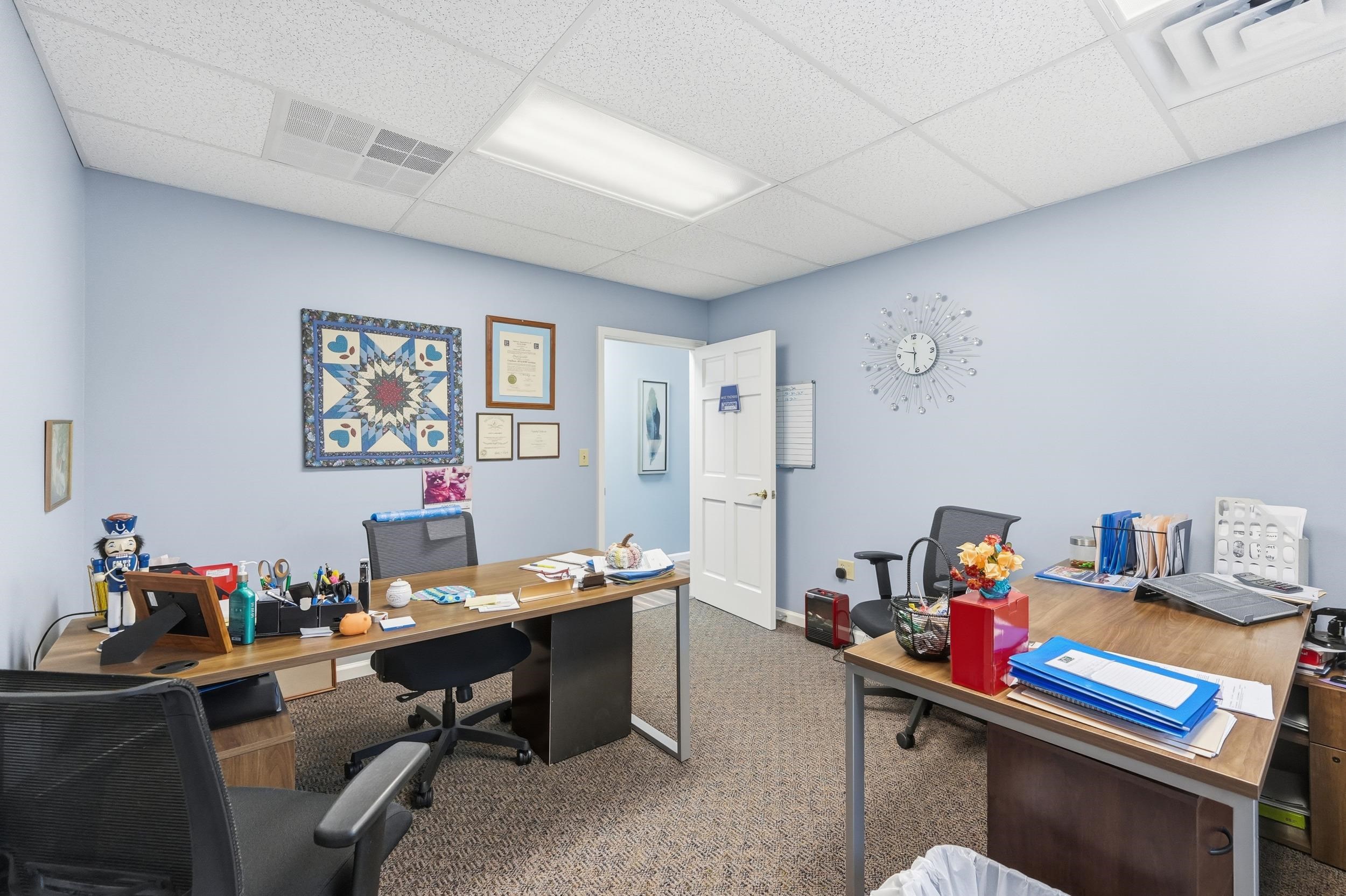 Carpeted home office with a drop ceiling and baseboards