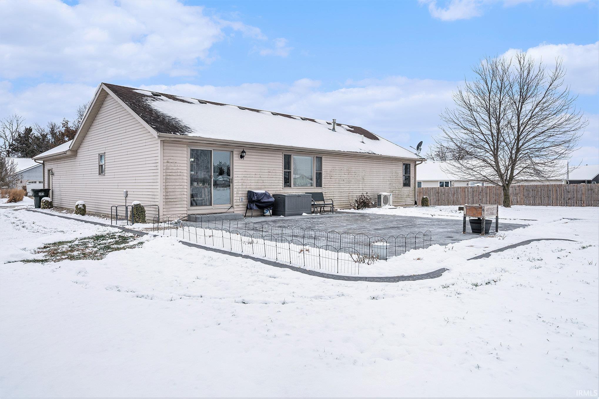 Snow covered rear of property featuring a patio area